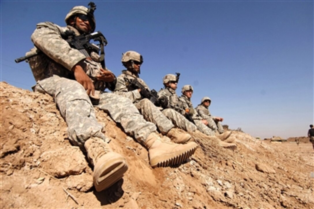 U.S. Army soldiers and Iraqi army soldiers sit on a dirt berm as they take a break during training at Tanmiya, Iraq, on Feb. 14, 2008.  Soldiers from the U.S. Army's 0832 Military Transition Team are training Iraqi army soldiers from the 2nd Light Infantry Battalion, 3rd Brigade Combat Team, 8th Army Division.  