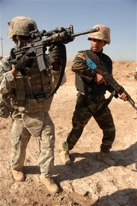Pfc. John Henry (left) shows an Iraqi soldier how to advance forward during training at Tanmiya, Iraq, on Feb. 14, 2008.  Henry and his fellow soldiers from the U.S. Army's 0832 Military Transition Team are training Iraqi army soldiers from the 2nd Light Infantry Battalion, 3rd Brigade Combat Team, 8th Army Division.  