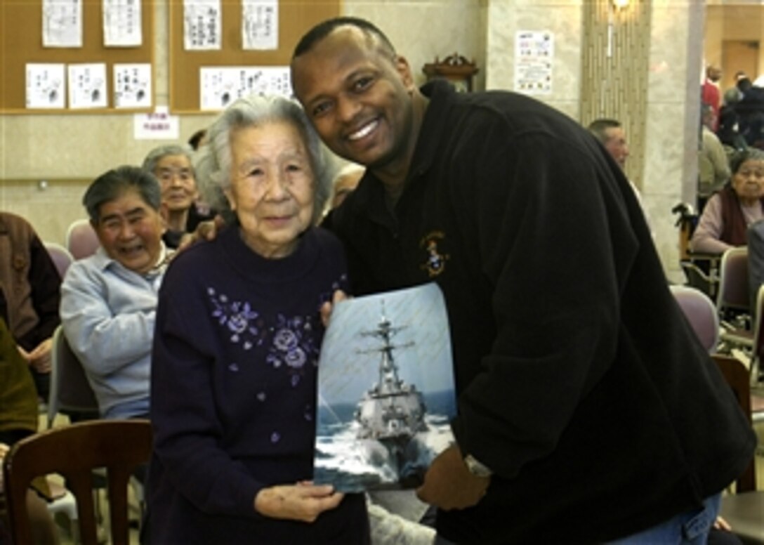 U.S. Navy Cdr. Anthony L. Simmons, commanding officer of Arleigh Burke-class guided missile destroyer USS Lassen, presents an autographed photo of the ship to residents of Nozomi No Mori, a senior citizens home in Nagasaki, Japan, Feb. 18, 2008.Simmons and members of his crew visited the home during a community relations project, where they spent quality time with the residents. 