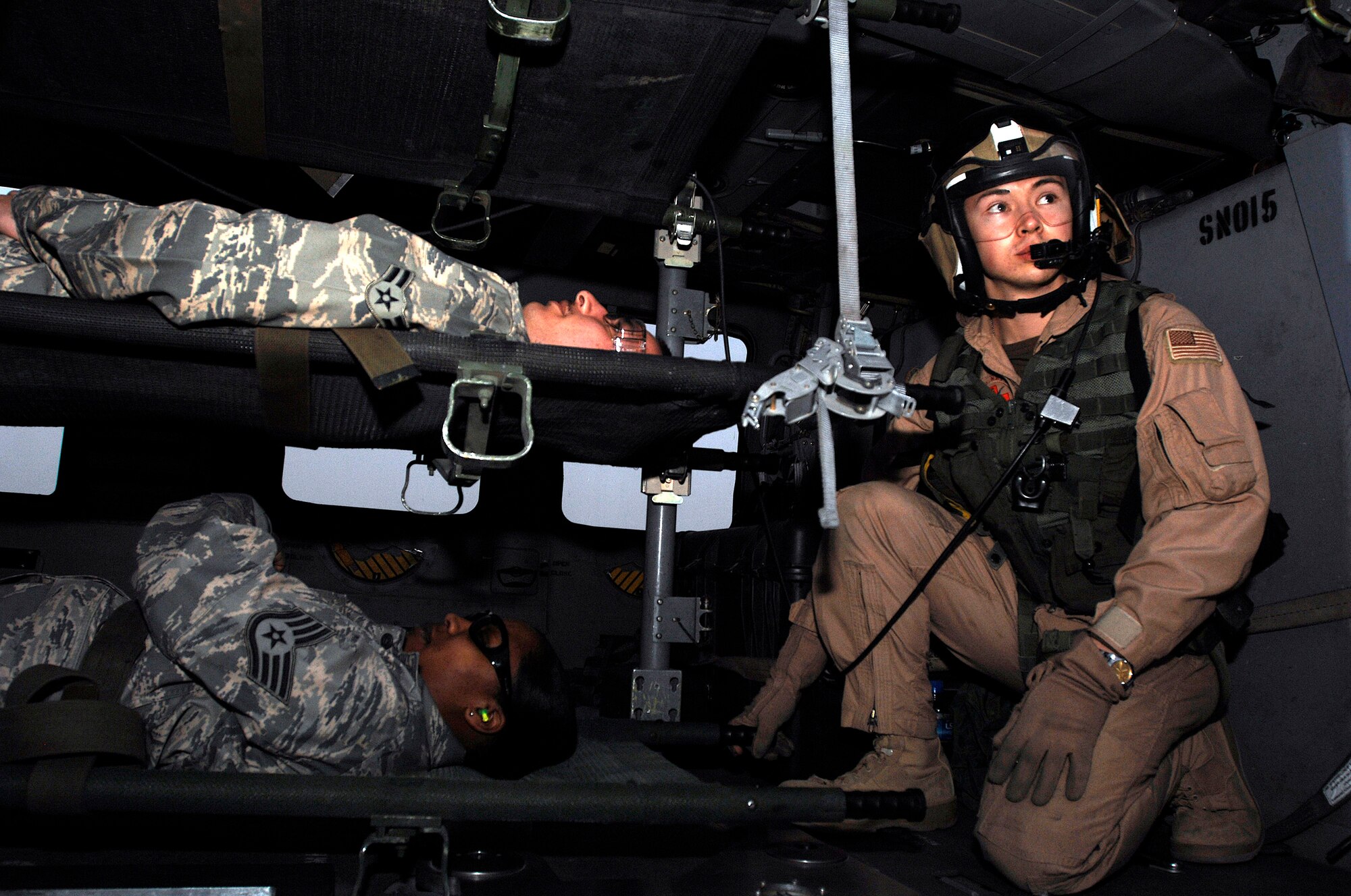 Navy Petty Officer 3rd Class Eric Uhden (right) gazes out while Airman 1st Class Edward Cuza and Staff Sgt. Siobahn Simon wait to be extracted from a Navy MH-60 Sierra during litter management system training Feb. 18 at a Southwest Asia air base. The training familiarized medics on the loading and extracting techniques of patients for medical evacuation missions in support of operations Enduring Freedom and Iraqi Freedom. Airman Cuza and Sergeant Simon are assigned to the 386th Expeditionary Medical Group. (U.S. Air Force photo/Staff Sgt. Patrick Dixon) 
