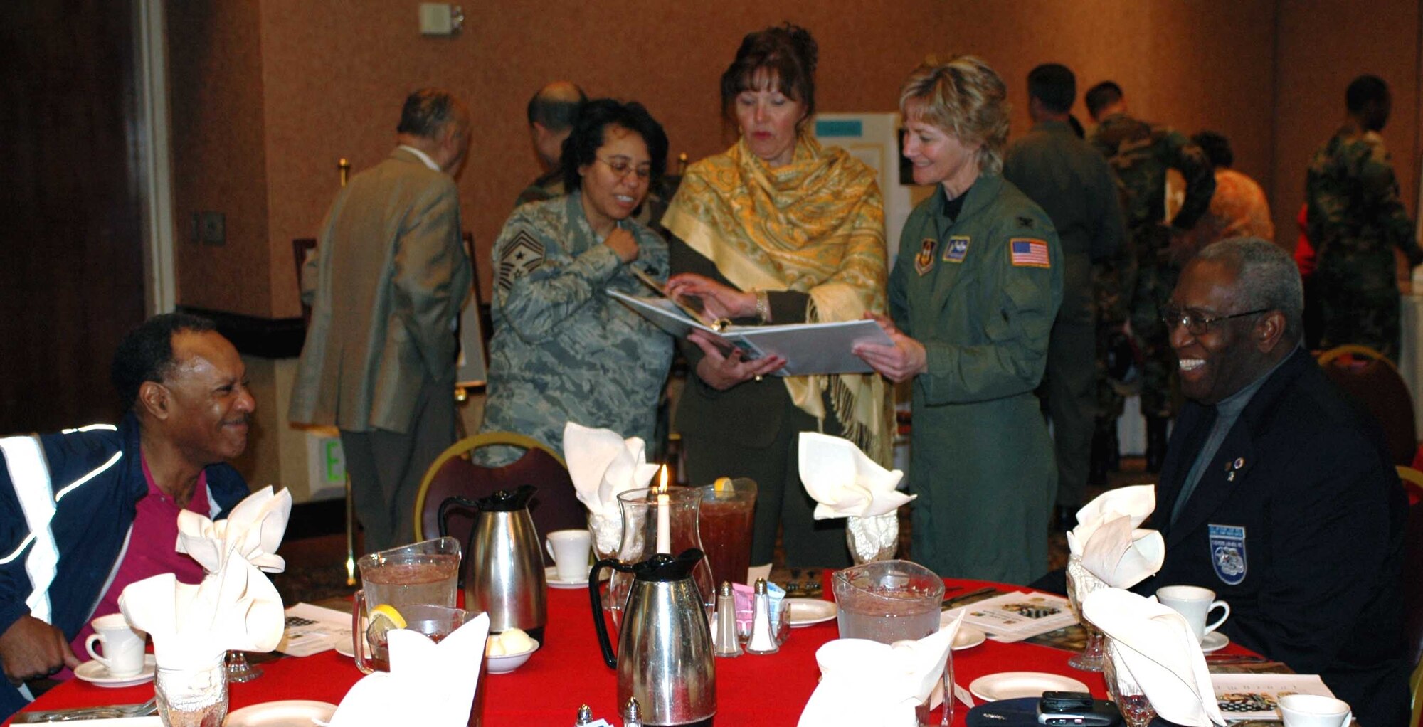 Col. Maryanne Miller, (right), 349th Air Mobility Wing commander, looks over photos with Chief Master Sgt. Christine Taylor, (left), 349th AMW command chief, and a Tuskegee Airman family member during the Tuskegee Airmen Luncheon at the Delta Breeze Club Feb. 19. The luncheon, sponsered by the African American Heritage Committee, was held in honor of Black History Month. (U.S. Air Force photo/Airman 1st Class Kristen Rohrer)

