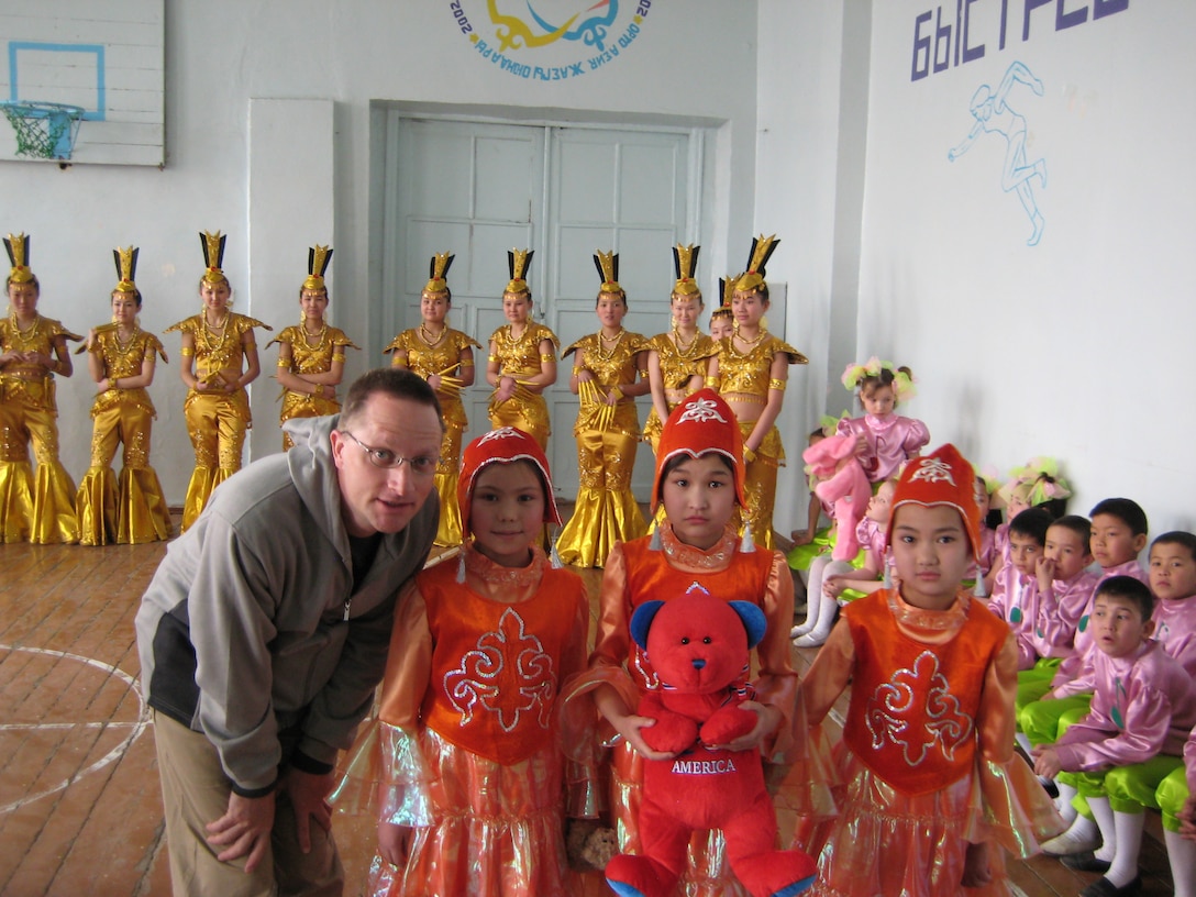TSGt Andrew Benton, piano player for the CENTAF band "Live Round," poses with some Kyrgystani children during a Spring '08 deployment to Africa and Southwest Asia.