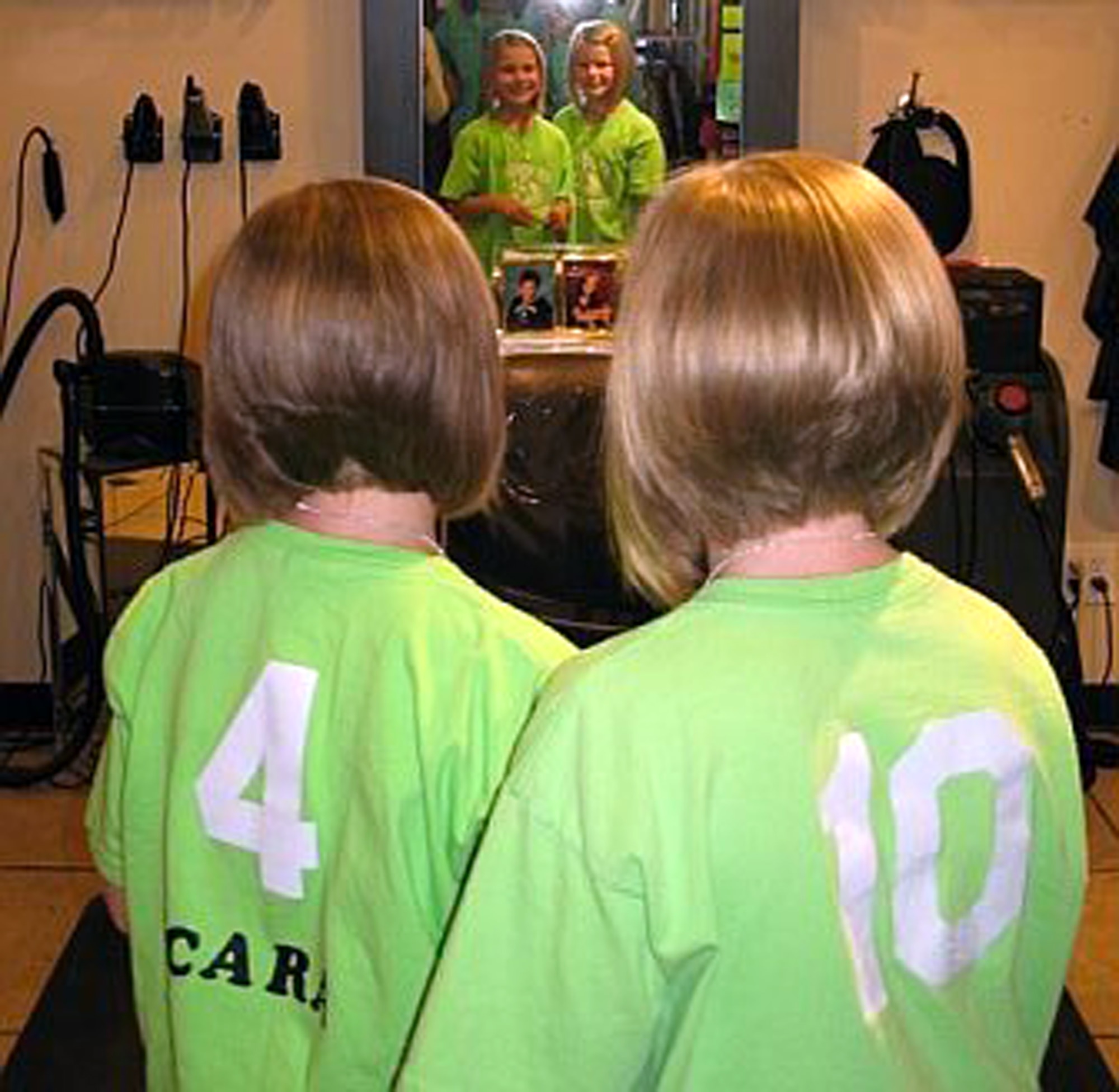 MOUNTAIN HOME AIR FORCE BASE, Idaho -- Cara McFarland and Anna Brooke Barfield look at themselves in the mirror after cutting their hair. The hair was donated to charity. The girls decided to donate their hair to children suffering from illnesses and going through chemotherapy treatments. (Courtesy photo)