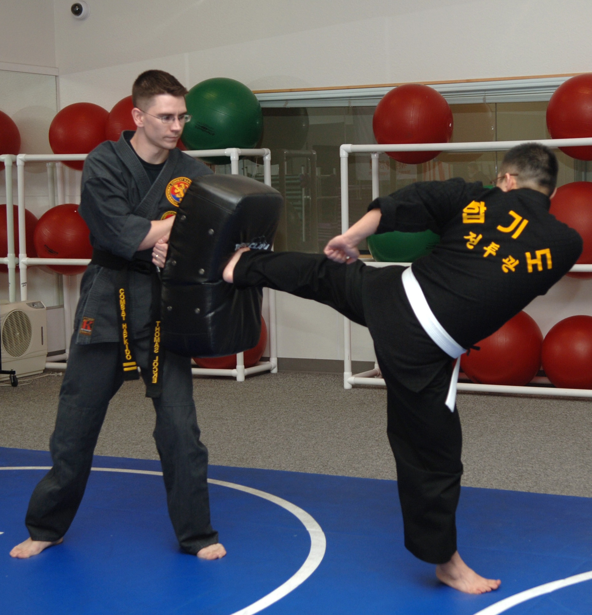 FAIRCHILD AIR FORCE BASE, Wash. -- Airman 1st Class Gyuseok James Kang, 92nd Communications Squadron, practices a side kick as instructed by Staff Sgt. Thomas Locke, 92nd Communications Squadron network administrator, during the Combat Hapkido class taught at the base Fitness Center Feb. 5. The Combat Hapkido class, which teaches self defense, is offered Tuesdays and Thursdays from 6 to 8 p.m. at the Fitness Center. (U.S. Air Force photo / Senior Airman Jocelyn Ford)