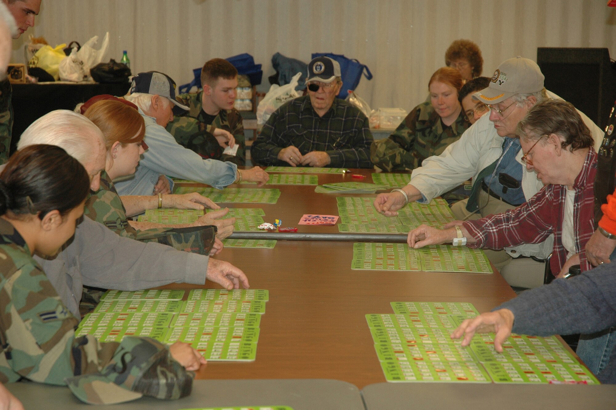 Students from the First Term Airmen Center aid residents from Sim's Veteran Home while playing bingo on Valentines Day.  To help with the veteran's hand-eye coordination, the Airmen repeat the number and point out numbers missed by the residents. (U.S. photo by Airman 1st Class Anthony J. Hyatt)