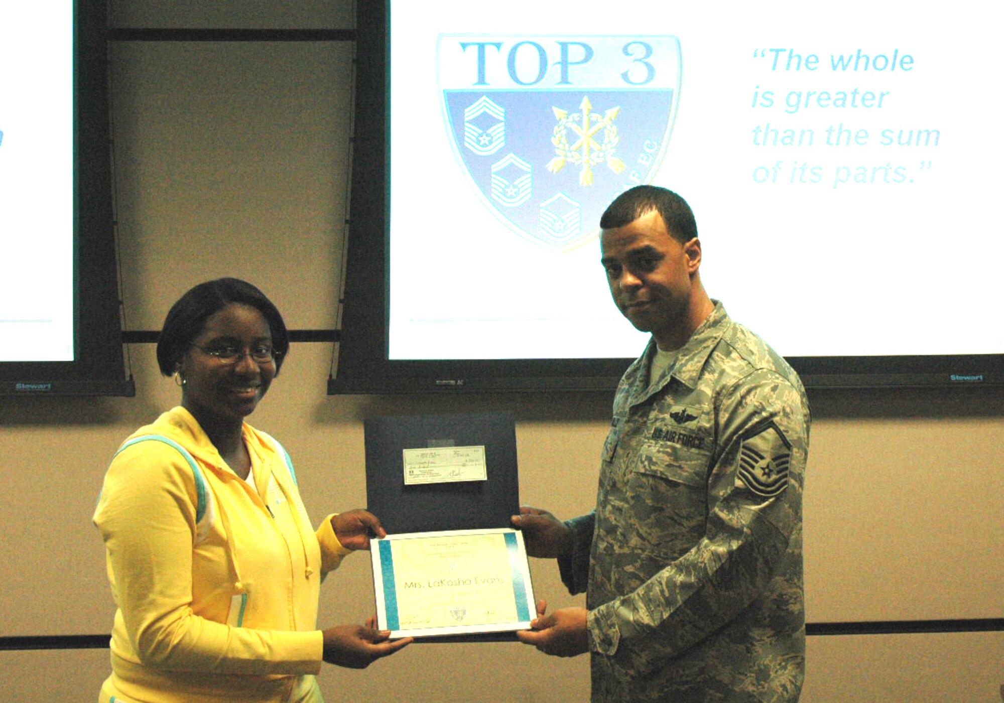 Mrs. LaKosha Evans, U.S. Air Force Expeditionary Center spouse, receives a $500 scholarship from the Center's Top Three with Master Sgt. Troy Coville, Top Three president presenting, during the group's meeting Feb. 14 in the Center on Fort Dix.  The USAF EC Top Three presents a scholarship to one of the Center's military spouses who attend college twice a year.  Mrs. Evans is the first recipient for 2008.  (U.S. Air Force Photo/Tech. Sgt. Scott T. Sturkol)