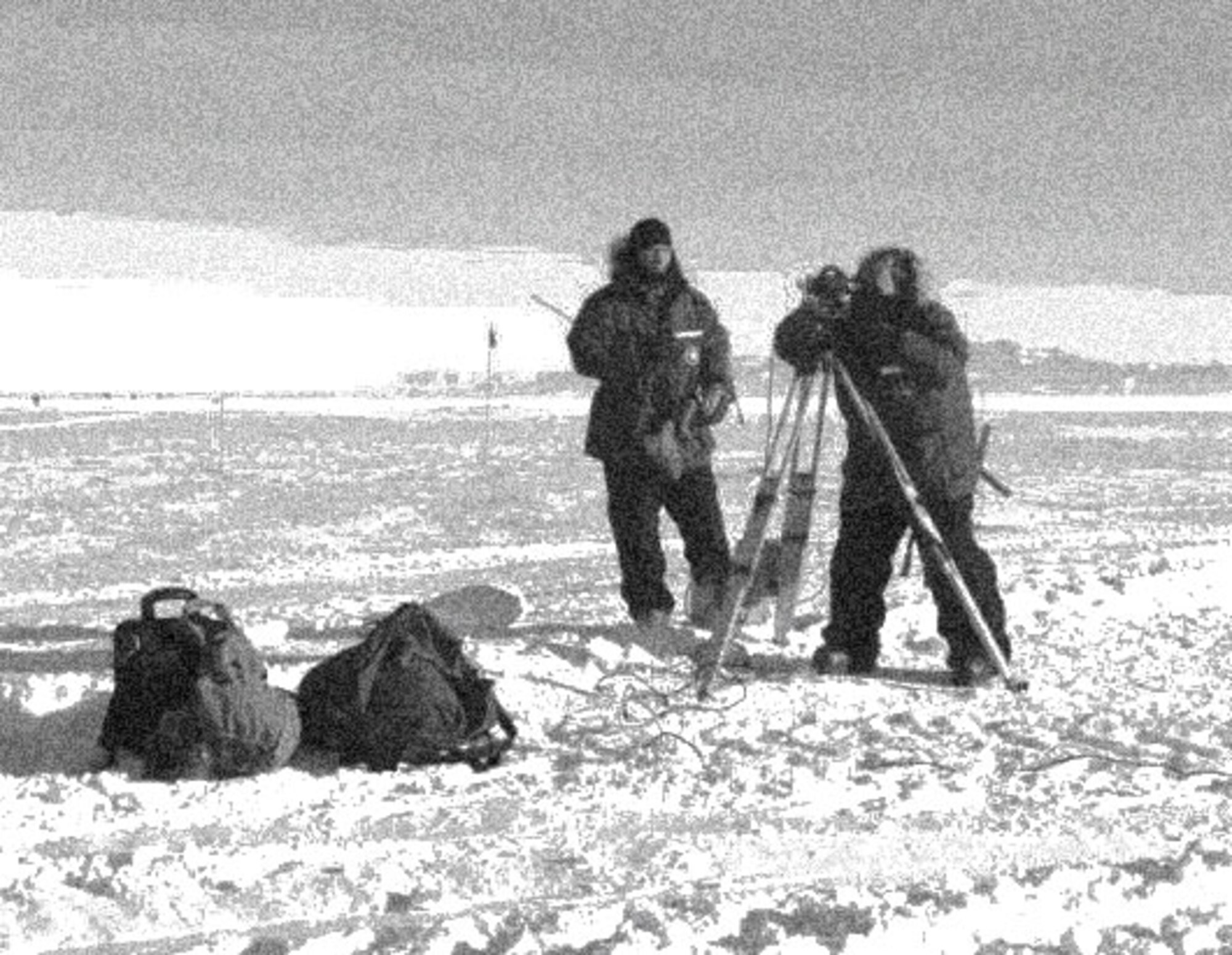 Two FAA members operate the theodolite equipment in Antarctica. This equipment transmits an aircraft position correction signal to the "ice box" in the C-130 aircraft. 
