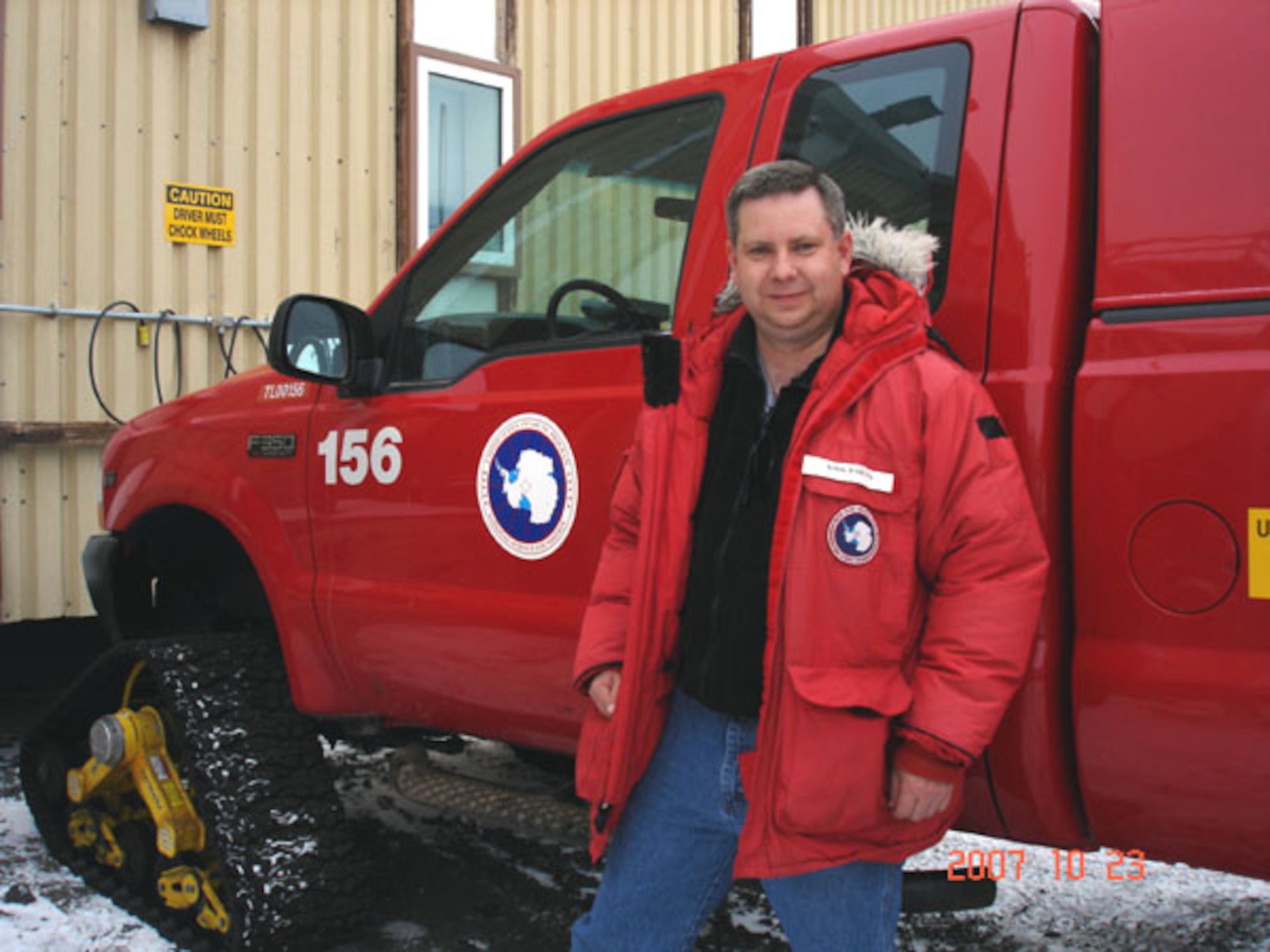 Master Sgt. Kirk Babcock stands beside one of the many specially outfitted trucks used to transport those stationed at McMurdo Station, Antarctica. Note the track used for front wheels.