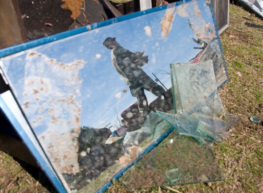 Capt. Joseph Timberlake is seen through a mirror as he collects debris amongst the wreckage of a home Feb. 19 in Prattville, Ala. More than 65 Officer Training School basic officer trainees and 20 other Airmen assigned to Maxwell Air Force Base, Ala., volunteered to help organize and clear debris from the city located 15 miles northwest of the base after the town was hit by a tornado. Latest estimates indicate that more than 150 home were destroyed and 760 homes were damaged in a series of storms with 150 mph winds. Of those homes, approximately 25 military homes were destroyed and 170 were damaged. Captain Timberlake is an Officer Training School instructor. (U.S. Air Force photo/Master Sgt. Scott Moorman) 

