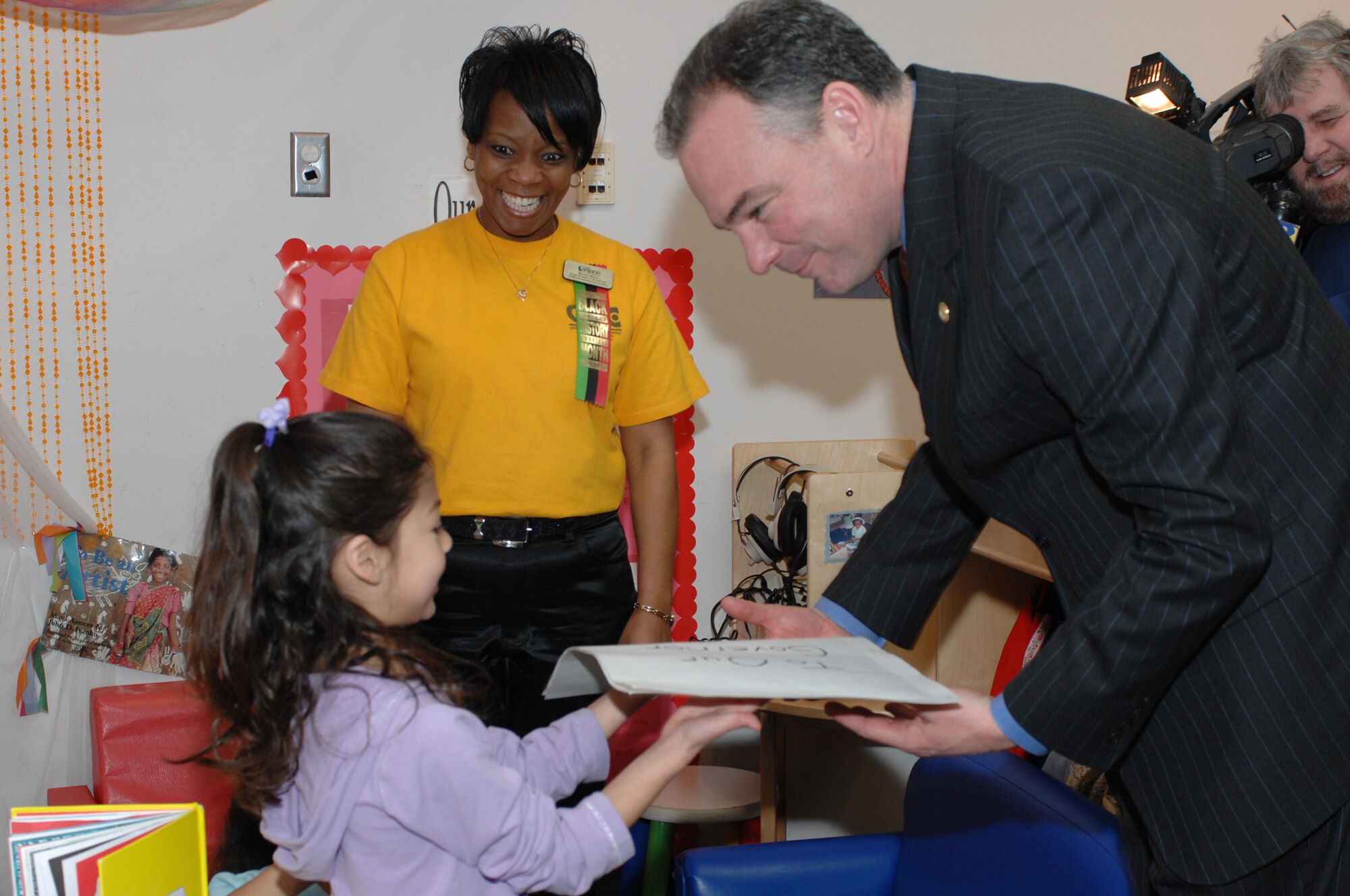 LANGLEY AIR FORCE BASE, Va. -- Angelina Marroquin, daughter of Senior Airman Justin Marroquin, 1st Communications Squadron, presents Gov. Tim Kaine with a card and photo of the children from Room 148 at the Russ Child Development Center Feb. 20, as Ms. Wendy Moore looks on. The children from Rom 148 are part of Gov. Kaine’s Start Strong Initiative, which teams Virginia communities with private, faith-based, home-based and military providers in an effort to provide quality education experiences for 4-year-olds. Gov. Kaine visited the CDC to see the children, discuss pre-kindergarten initiatives and budget proposals. (U.S. Air Force photo/Staff Sgt. April Wickes)