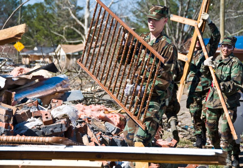 Officer Trainee Michael Hart carries whats left of a crib during a cleanup Feb. 19 after a Feb. 17 tornado ravaged Prattville, Ala. More than 65 Officer Training School basic officer trainees and 20 other Airmen assigned to Maxwell Air Force Base, Ala., volunteered to help organize and clear debris from the city located 15 miles northwest of the base. Base officials held an emergency town hall meeting Feb. 19 for victims of the disaster. Some of the representatives that attended the meeting included finance, chaplain, medical, Airman and Family Readiness Center, Air Force Aid Society, Child Development Center, Traffic Management Office and legal. The base's privatized housing developer, Pinnacle-Hunt also offered on-base housing options for military families needing immediate shelter. (U.S. Air Force photo/Master Sgt. Scott Moorman) 