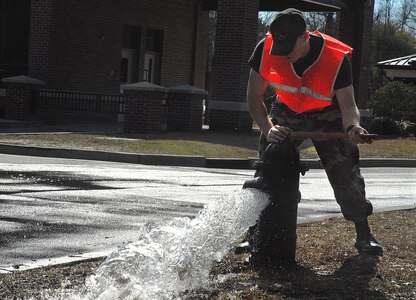 Airman Juan Ayon-Loza closes a fire hydrant by the front gate Wednesday.  Airman Ayon-Loza is a 437th Civil Engineer Squadron utilities apprentice who was closing the hydrant after making sure the water line pressure was shut off so a crew could replace a gas line. (U.S. Air Force photo/Airman 1st Class Melissa White)