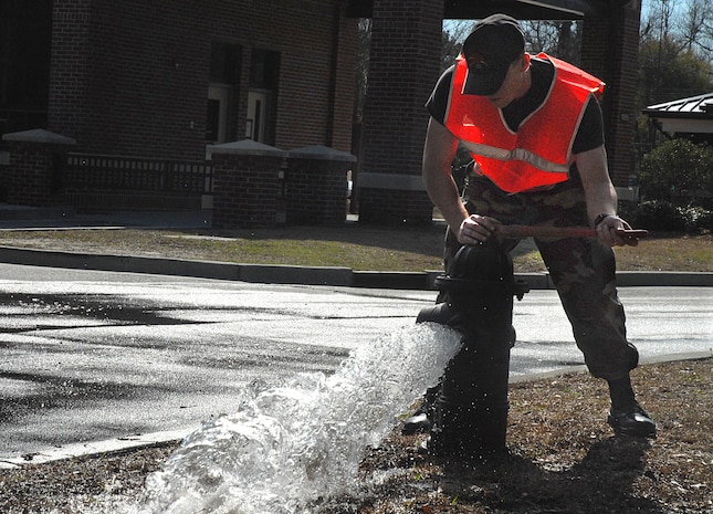 Airman Juan Ayon-Loza closes a fire hydrant by the front gate Wednesday.  Airman Ayon-Loza is a 437th Civil Engineer Squadron utilities apprentice who was closing the hydrant after making sure the water line pressure was shut off so a crew could replace a gas line. (U.S. Air Force photo/Airman 1st Class Melissa White)