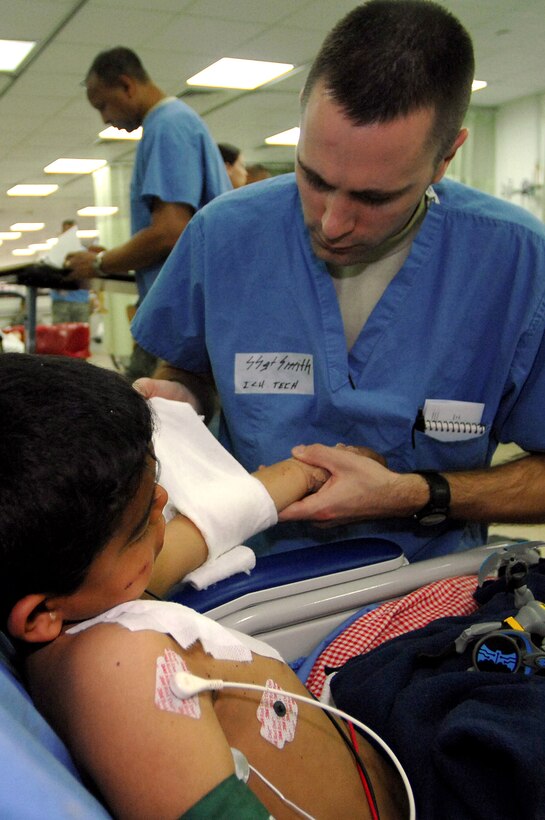 Staff Sgt. Delbert Smith treats an Iraqi child at the Air Force Theater Hospital Feb. 19 at Balad Air Base, Iraq. The child was injured by an 82-millimeter mortar round, which struck a soccer field where he and other children were playing in the village of Al Jumia. A 12-year-old Iraqi child was killed and seven others were wounded during the attack. The village lies to the north of Balad AB. Four rounds were launched toward the base, but all fell short. However, two of the rounds struck the field where children were playing. Sergeant Smith is a 332nd Expeditionary Medical Operations Squadron intensive care unit technician deployed from Keesler Air Force Base, Miss. (U.S. Air Force photo/Senior Airman Julianne Showalter) 