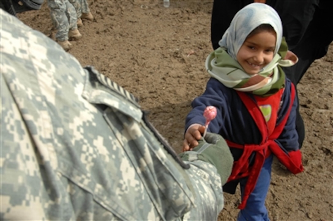 A U.S. Army soldier gives an Iraqi girl a lollipop during a cooperative medical exchange in the town of Al Abur in the Diyala Province of Iraq on Feb 15, 2008.  Soldiers from the Armyís 2nd Squadron, 1st Cavalry Regiment are conducting the medical exchange along with Iraqi army medical personnel.  
