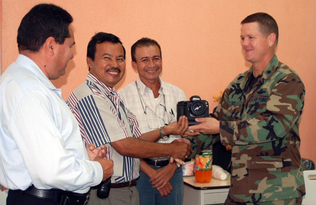 Air Force Lt. Col. Lawrence Ott, Joint Task Force-Bravo deputy commander delivers an assortment of cameras and lenses to journalism department staff members Jose Gomez, Julio Cesar Turcios and Ildefonso Marcia at Universitario Regional del Centro, Comayagua, Honduras. The equipment was made available using a Defense Reutilization and Marketing Service program. 