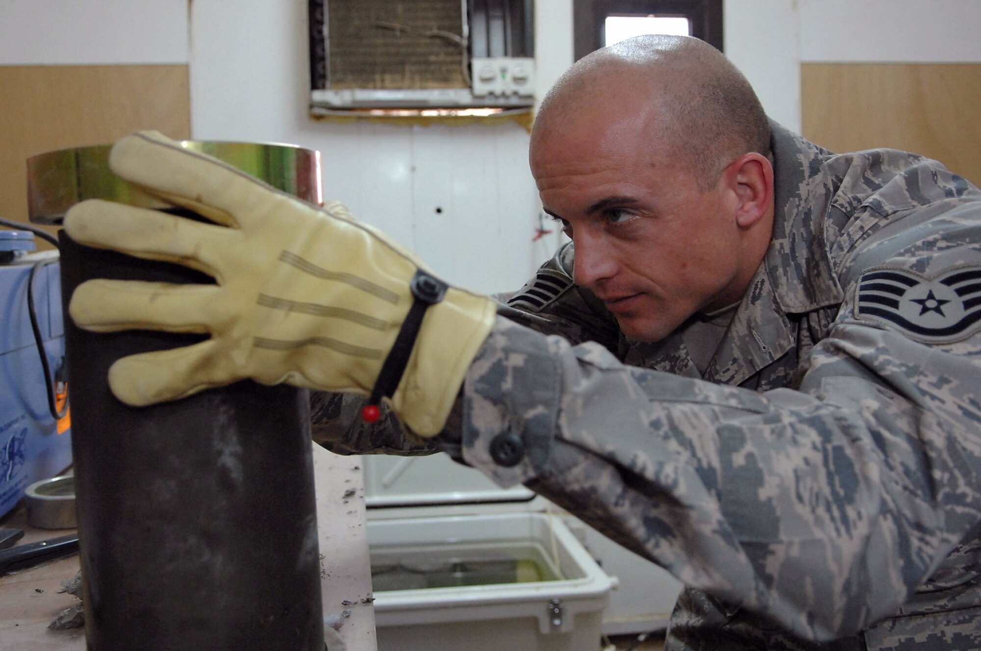 Staff Sgt. Jack Jenkins places brass ends on both sides of a concrete cylinder sample taken from the new Housing 6 area shoppette foundation Feb. 21 at Balad Air Base, Iraq. The brass ends are part of a strength test machine that is used to compress concrete to determine if it is suitable for use in building foundations or flightline areas. Sergeant Jenkins is a 332nd Civil Engineer Squadron engineering assistant deployed from Ellsworth Air Force Base, S.D. (U.S. Air Force photo/Senior Airman Julianne Showalter) 
