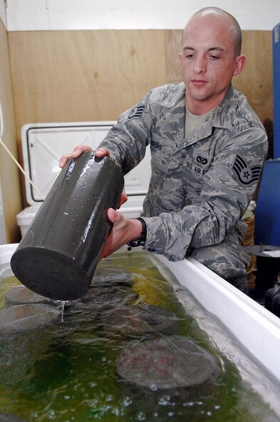 Staff Sgt. Jack Jenkins pulls out a concrete cylinder sample that was taken from the new Housing 6 area shoppette foundation Feb. 21 at Balad Air Base, Iraq. The concrete will be cured for seven days in a water bath before a strength test is performed on it, during which the cylinder must endure 4,500 pounds per square inch of compression. Sergeant Jenkins is a 332nd Civil Engineer Squadron engineering assistant deployed from Ellsworth Air Force Base, S.D. (U.S. Air Force photo/Senior Airman Julianne Showalter) 
