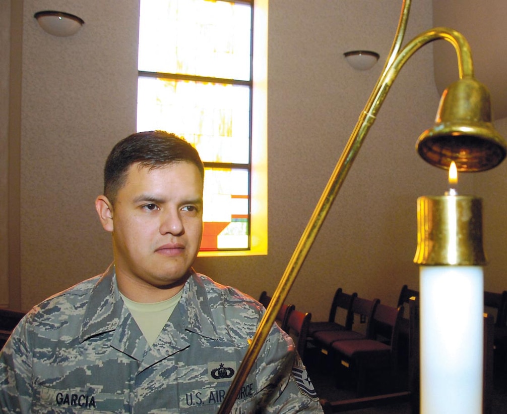 Tech. Sgt. Jason Garcia snuffs out a candle in the main sanctuary after catholic mass services held at Chapel One on Feb. 18. Sergeant Garcia is the 316th Wing Chapel One Readiness NCOIC. (US Air Force/Bobby Jones)