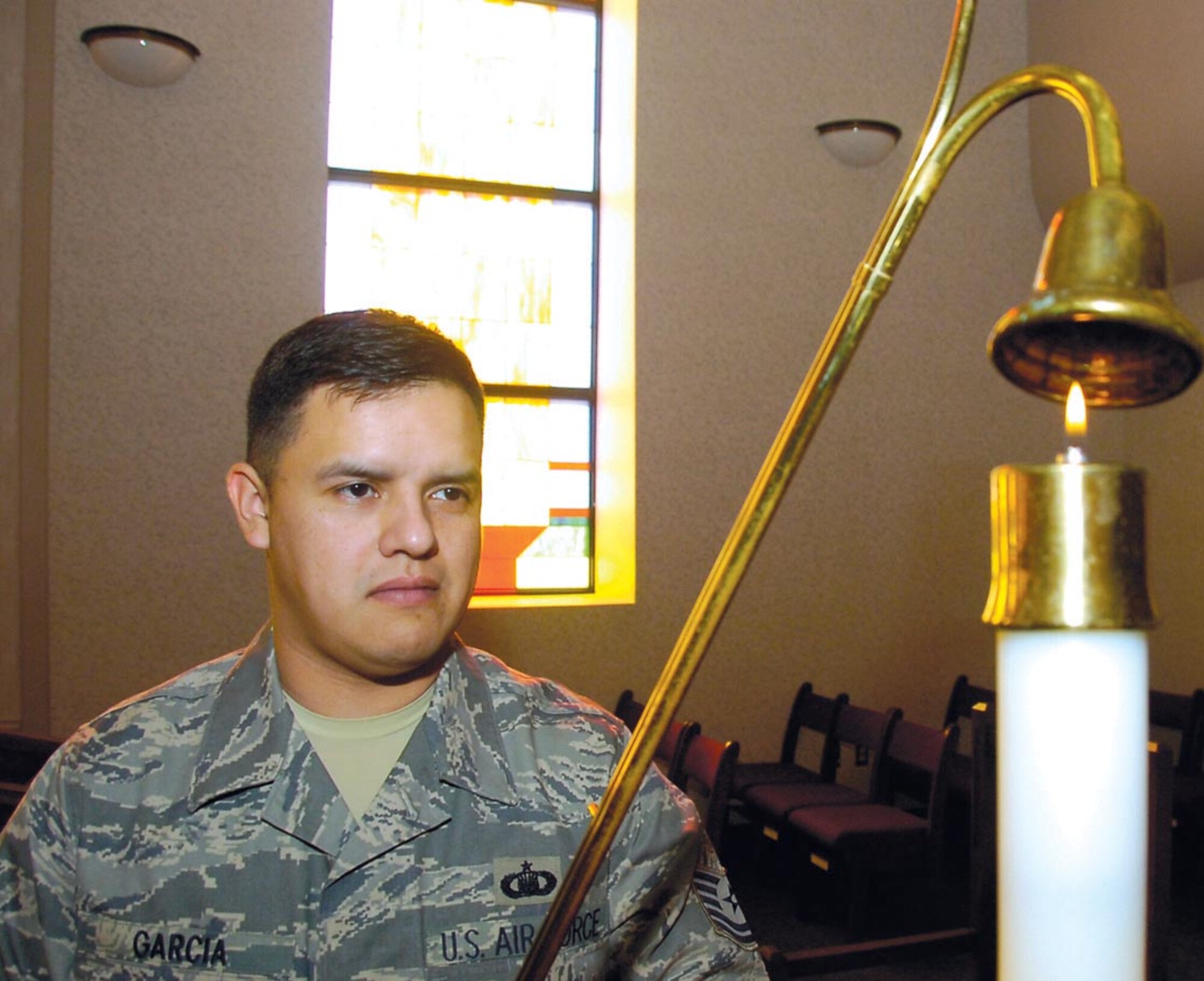 Tech. Sgt. Jason Garcia snuffs out a candle in the main sanctuary after catholic mass services held at Chapel One on Feb. 18. Sergeant Garcia is the 316th Wing Chapel One Readiness NCOIC. (US Air Force/Bobby Jones)