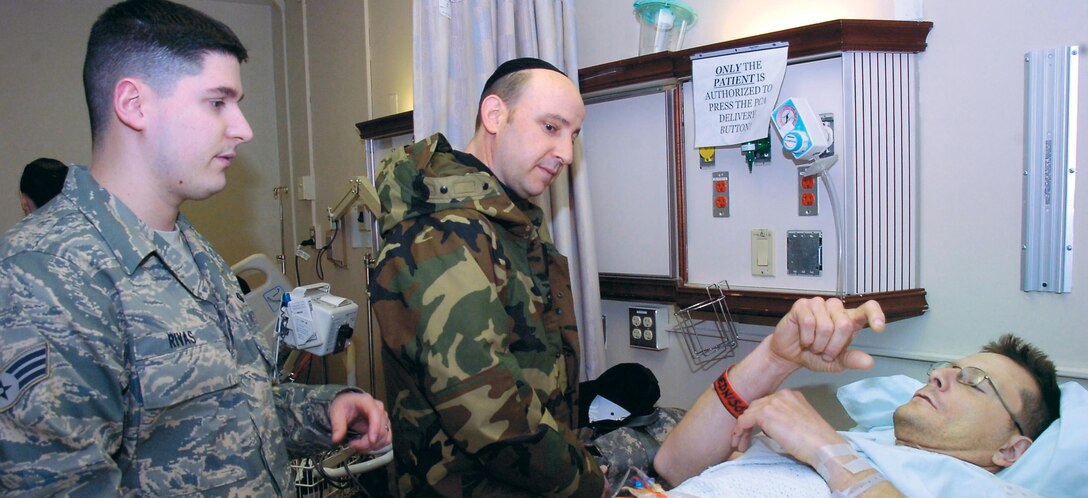 Senior Airman Frank Rivas and Ch. (Capt.) Andrew Cohen, talk beside Army Pfc. Darren Riley, after his return from duty in support of Operation Enduring Freedom and Operation Iraqi Freedom  at the 79th Aeromedical Staging Flight on Feb. 18. (US Air Force/Bobby Jones)