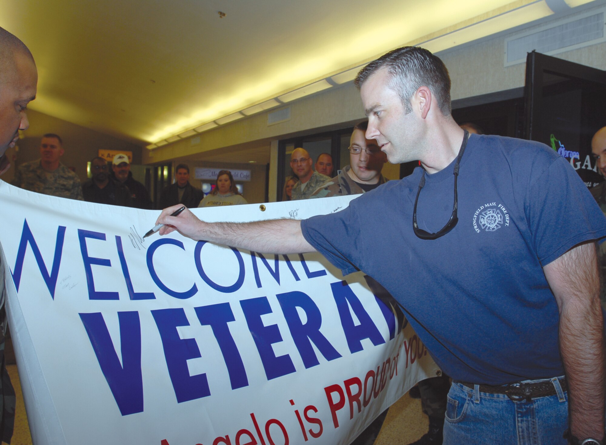 Master Sgt. Matthew Simmons, a fire instructor with the Department of Defense Louis F. Garland Fire Academy, signs the welcome back poster at San Angelo Regional Airport Mathis Field as he returns from a deployment Feb. 15. Sergeant Simmons was part of the team tasked with constructing the first Iraqi National Fire Academy in support of Operation Iraqi Freedom. (U.S. Air Force photo by Staff Sgt. Angela Malek)