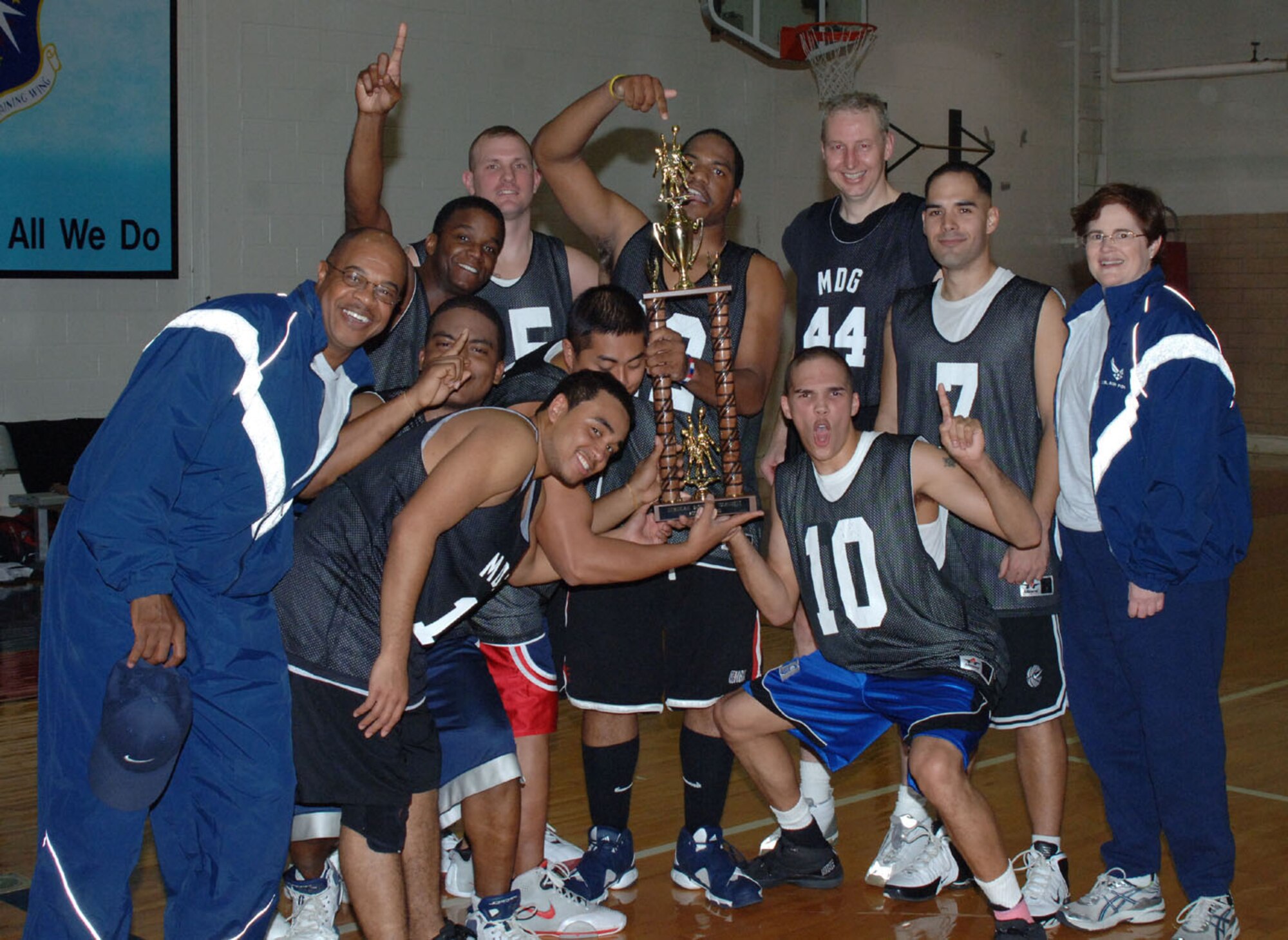 The 14th Medical Group poses with their trophy immediately following their victory over the 37th/41st Flying Training Squadron in the intramural basketball championship game Tuesday night. The MDG won its second straight basketball championship trophy.  The team is seen here with Col. Susan Hall, 14th MDG commander, and Chief Master Sgt. Leon Hall, 14th MDG Superintendent. (U.S. Air Force photo by Airman 1st Class Danielle Hill)