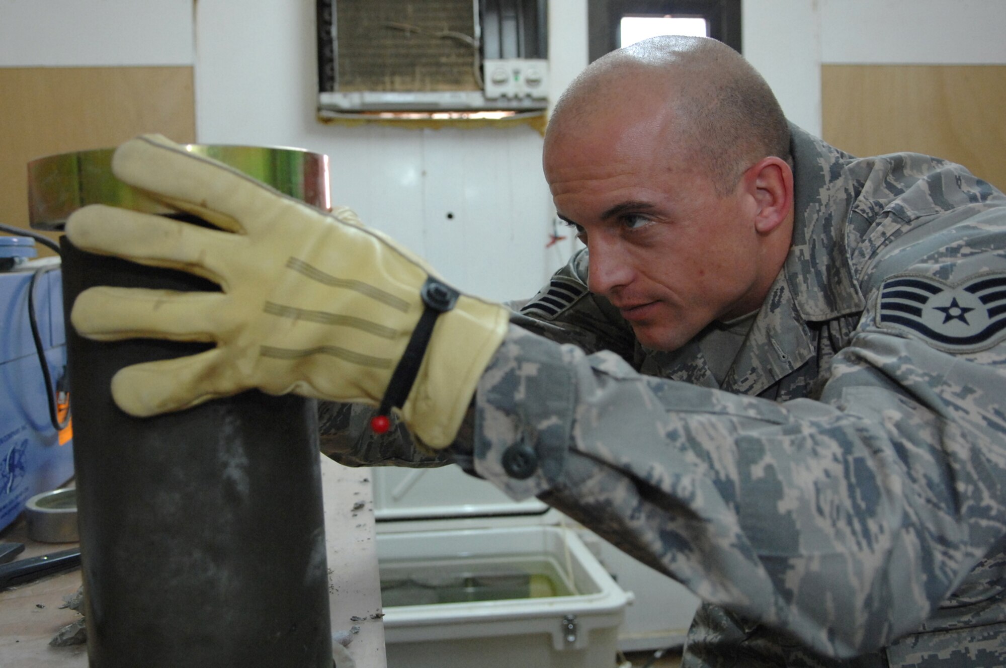BALAD AIR BASE, Iraq -- Staff Sgt. Jack Jenkins, 332nd Civil Engineer Squadron engineering assistant, places brass ends on both sides of a concrete cylinder sample taken from the new Housing 6 area shoppette foundation here, Feb. 21. The brass ends are part of a strength test machine that is used to compress concrete to determine if it is suitable for use in building foundations or flight line areas. Sergeant Jenkins is deployed from Ellsworth Air Force Base, S.D. (U.S. Air Force photo/ Senior Airman Julianne Showalter)