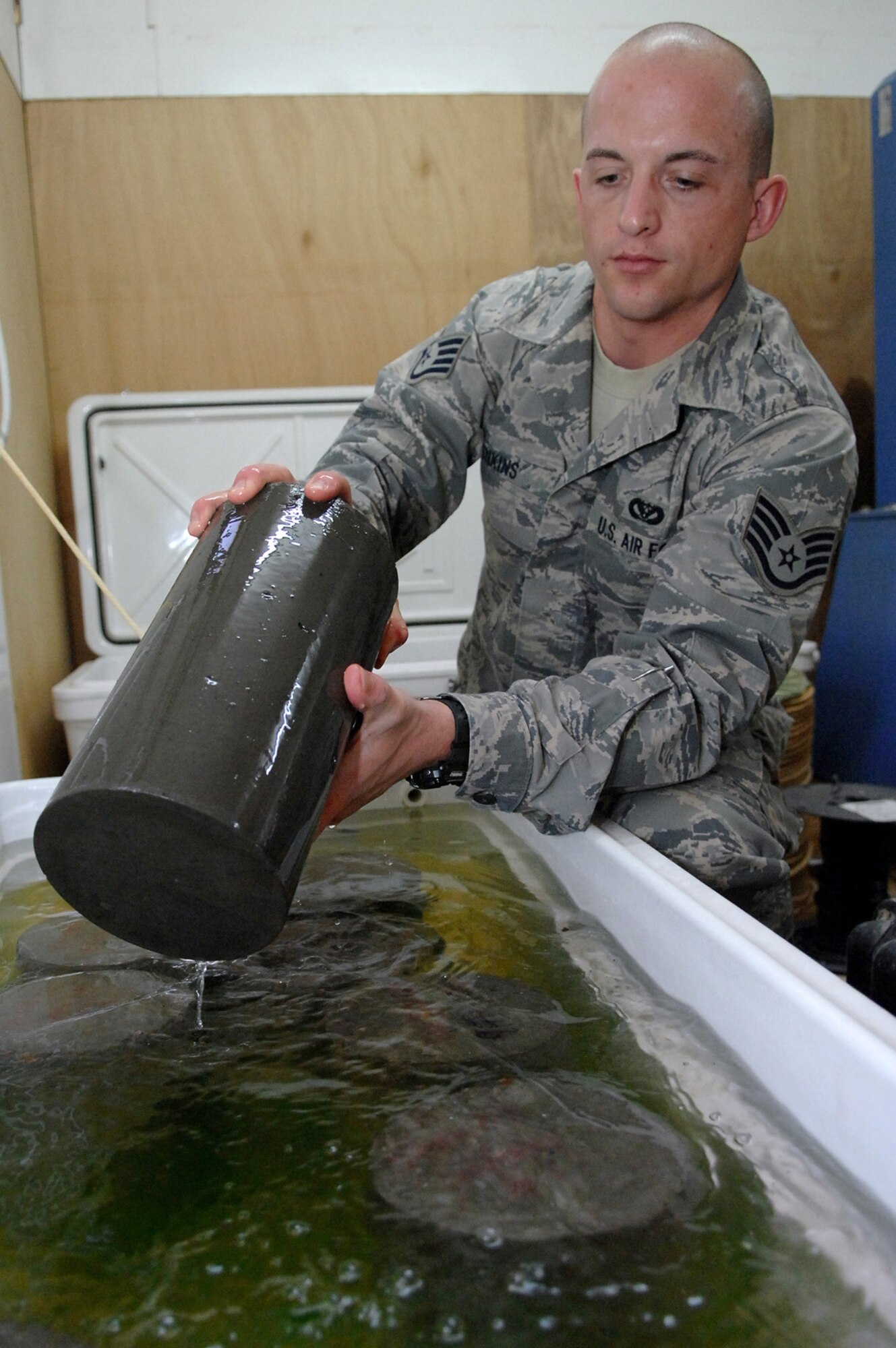 BALAD AIR BASE, Iraq -- Staff Sgt. Jack Jenkins, 332nd Civil Engineer Squadron engineering assistant, pulls out a concrete cylinder sample that was taken from the new Housing 6 area shoppette foundation here, Feb. 21. The concrete will be cured for seven days in a water bath before a strength test is performed on it, during which the cylinder must endure 4,500 pounds per square inch of compression. Sergeant Jenkins is deployed from Ellsworth Air Force Base, S.D. (U.S. Air Force photo/ Senior Airman Julianne Showalter)