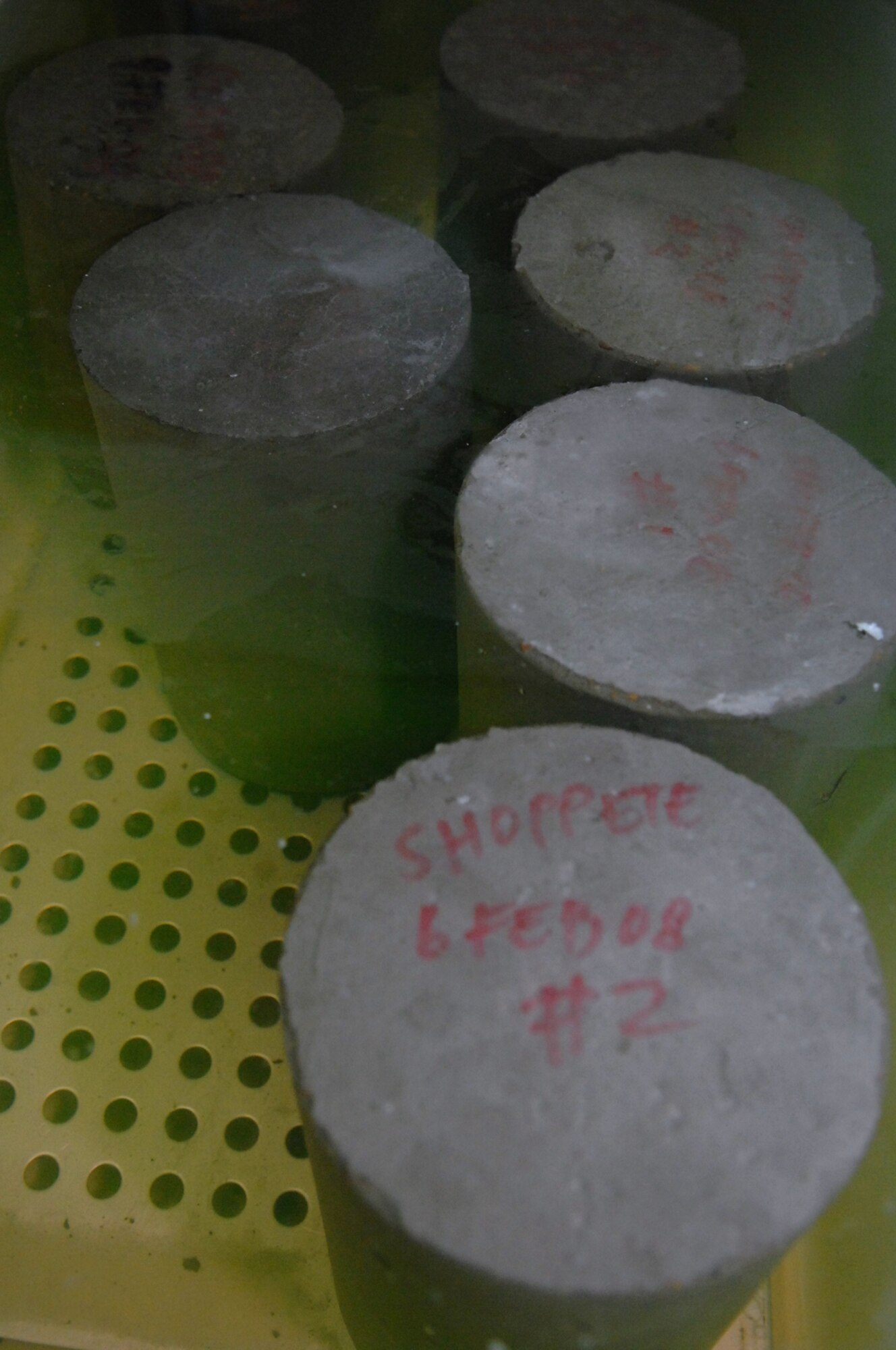 BALAD AIR BASE, Iraq -- Twenty-pound concrete cylinder samples are taken from various construction locations around base. The samples are tested to ensure the concrete can withstand the pressure of 6,000 pounds per square inch for flight line uses and 4,500 psi for building foundations. These tests confirm aircraft or buildings can be put on concrete surfaces without the concrete cracking or sinking. The cylinders are cured for 24 hours and then placed in a water bath for seven days before putting them though a strength test machine. On Feb. 21, a sample from the new Housing 6 area shoppette was tested and passed the strength test. (U.S. Air Force photo/ Senior Airman Julianne Showalter) 