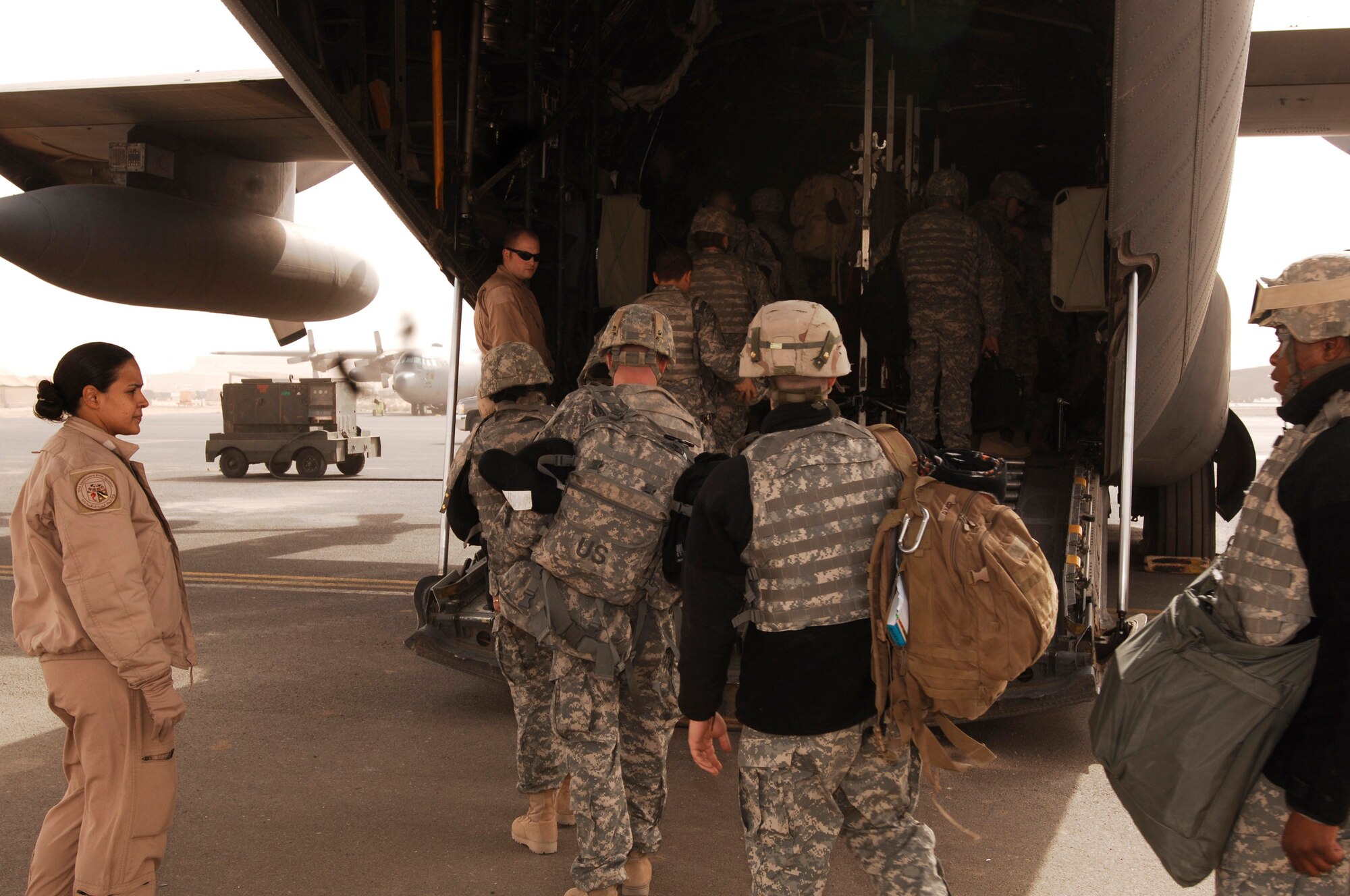 SOUTHWEST ASIA -- Technical Sgt. Sigrid Carrero-Perez (left) and Senior Airman Ian Hunt (center), C-130 loadmasters deployed with the 737th Expeditionary Airlift Squadron, guide servicemembers unto a C-130 Hercules Feb. 16, 2008, at an air base in the Persian Gulf Region. Loadmasters ensure the cargo, equipment, and passengers are safely transported to wherever the combatant commanders need them. Sergeant Carrero-Perez is deployed from Yokota Air Base, Japan and Airman Hunt is deployed from Dyess Air Force Base, Texas supporting Operations Enduring and Iraqi Freedom. (U.S. Air Force photo/ Staff Sgt. Patrick Dixon)