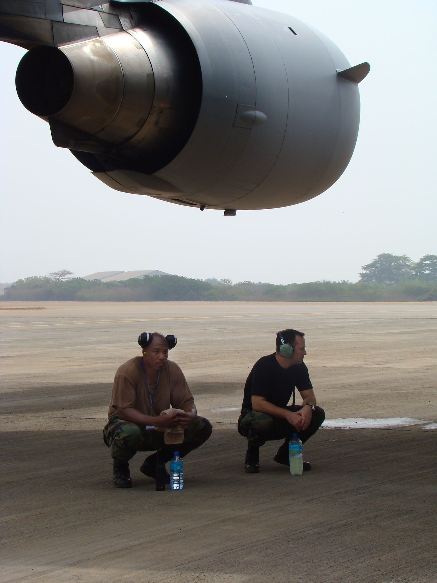 Two maintainers from the 768th Expeditionary Air Base Squadron here take a break from the sun Feb. 16. The C-17A Globemaster's wing span provides 170 feet of shade. Tech. Sgt. Richard Bowen, noncommissioned officer in charge of maintenance, and Staff Sgt. Brendon Risken, a crew chief, are both from the 621st Contingency Response Wing, McGuire AFB, N.J.