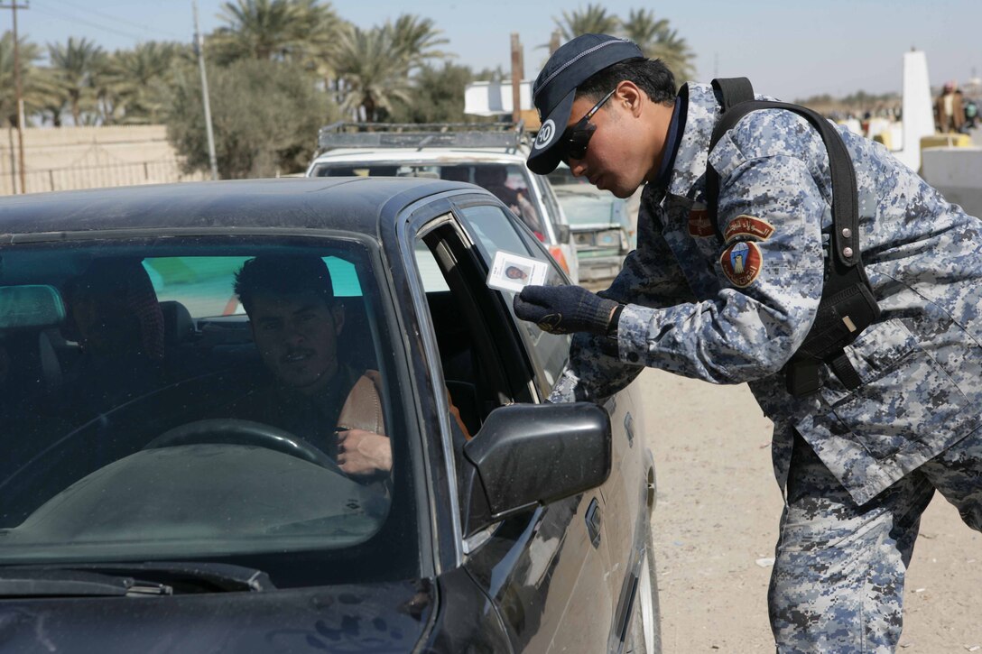 An Iraqi policeman checks a man’s identification card in al Anbar Province, Iraq, Feb. 2. Marines with Task Force 1st Battalion, 3rd Marine Regiment, Regimental Combat Team 1, and other Coalition forces are making operational adjustments to drawdown forces allowing Iraqi Security Forces take control of security in their cities