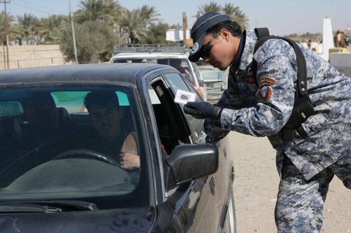 An Iraqi policeman checks a man’s identification card in al Anbar Province, Iraq, Feb. 2. Marines with Task Force 1st Battalion, 3rd Marine Regiment, Regimental Combat Team 1, and other Coalition forces are making operational adjustments to drawdown forces allowing Iraqi Security Forces take control of security in their cities