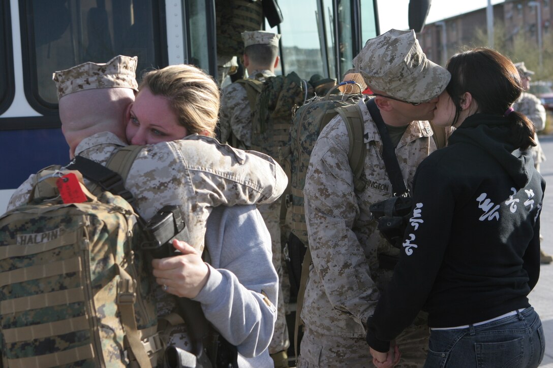 Sgt. Nathan Halpin, (left) a Boise, Idaho, native with 3rd Battalion, 4th Marine Regiment, hugs his girlfriend, Amanda Ward, as Cpl. Matt Harrington, a British Colombia, Canada, native with 3/4, kisses his wife, Erica, goodbye just before setting off on a deployment to Iraq from the Combat Center Feb. 25, 2008.  3/4, also nicknamed ?Darkside? for their call sign they adopted during the beginning of Operation Iraqi Freedom, will be deploying to western Al Anbar Province, Iraq.  They are tasked with mentoring, monitoring and training the Iraqi security forces, maintaining security and assisting the local leaders to become better governing officials for their local government.