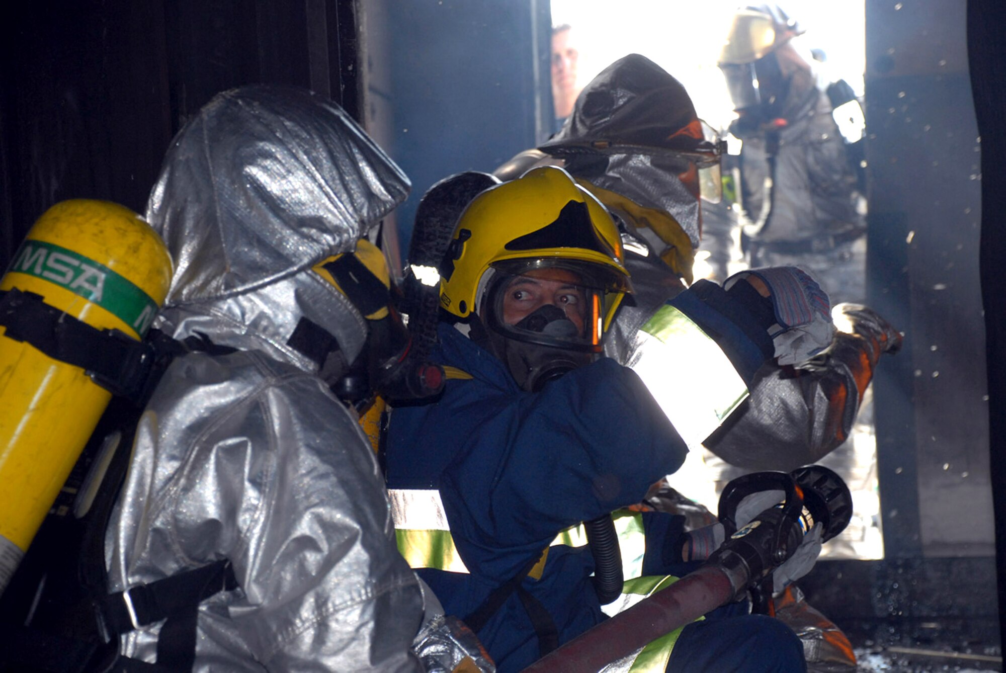 A civilian Honduran firefighter looks for the all-clear signal before pushing into a fire engulfed room at the Joint Task Force-Bravo "burn house," a two-level training structure constructed of concrete and metal. The firefighters are participating in a JTF-Bravo-sponsored firefighting subject matter expert exchange. To make the experience of entering a burning building as realistic as possible, firefighters start a controlled fire inside the structure which provides a smoky atmosphere and temperatures of 900 degrees at the fire's base and 1,400 at the ceiling. (U.S. Air Force photo/Tech. Sgt. William Farrow) 