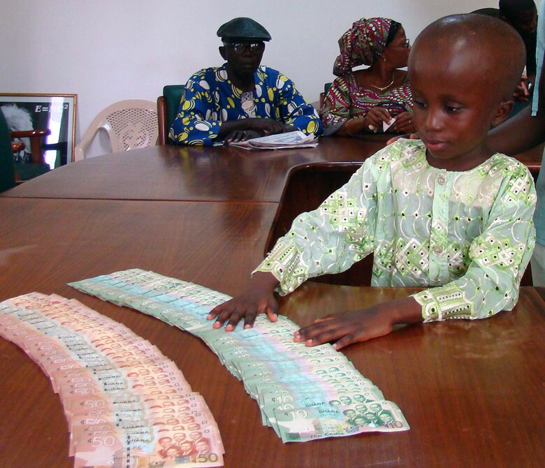 Alex Vadis Teye, 9, admires the money donated by American military members in Africa to pay for surgery he needs. Alex visited the Korle Bu Teaching Hospital in Ghana, Africa, Feb. 22 to accept the donation that came in response to his parents' plea for help. Alex suffers from hydrocephalus, a common birth defect which causes an excess of water in the brain. The U.S. military presence in Ghana is in support of President George Bush's visits to the continent. (U.S. Air Force photo/Tech. Sgt. Denise Johnson) 