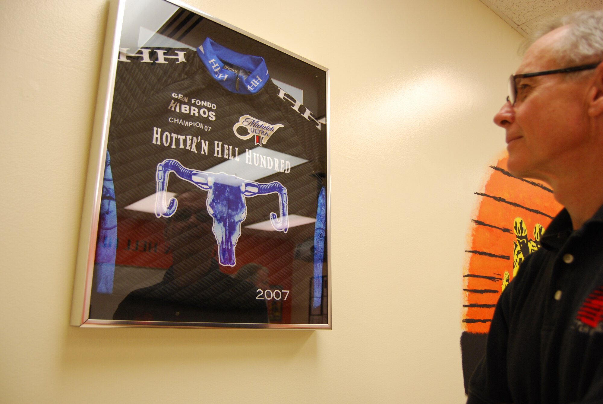 Roby Christie, former Hotter 'N Hell Hundred executive director, takes a look at a cycling jersey he donated to the 361st Training Squadron at Sheppard Air Force Base as part of their HHH-themed classroom. The room was dedicated Feb. 22, pairing the nation's largest single-day cycling event with the Air Force's single largest training base. Brig. Gen. Richard Devereaux, 82nd Training Wing commander, 82nd Training Group Commander Col. Steven Morani, Lt. Col. Scott Kelly, 361st TRS commander, current executive director Ben Filer and guests were also on hand for the dedication. (U.S. Air Force photo/John Ingle)