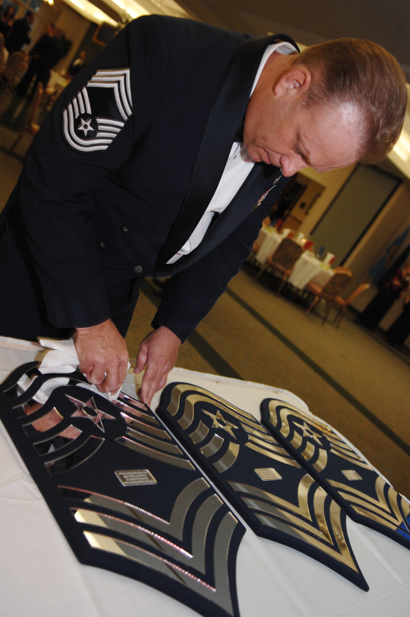 MOODY AIR FORCE BASE, Ga. – Chief Master Sgt. Eddie McNally, 23rd Mission Support Group superintendent, cleans a plaque before it is presented to a promoted chief master sergeant here during the chief induction ceremony Feb 23. Three of Moody's four newest chiefs were able to attend the ceremony. (U.S. Air Force photo by Senior Airman Angelita Lawrence)