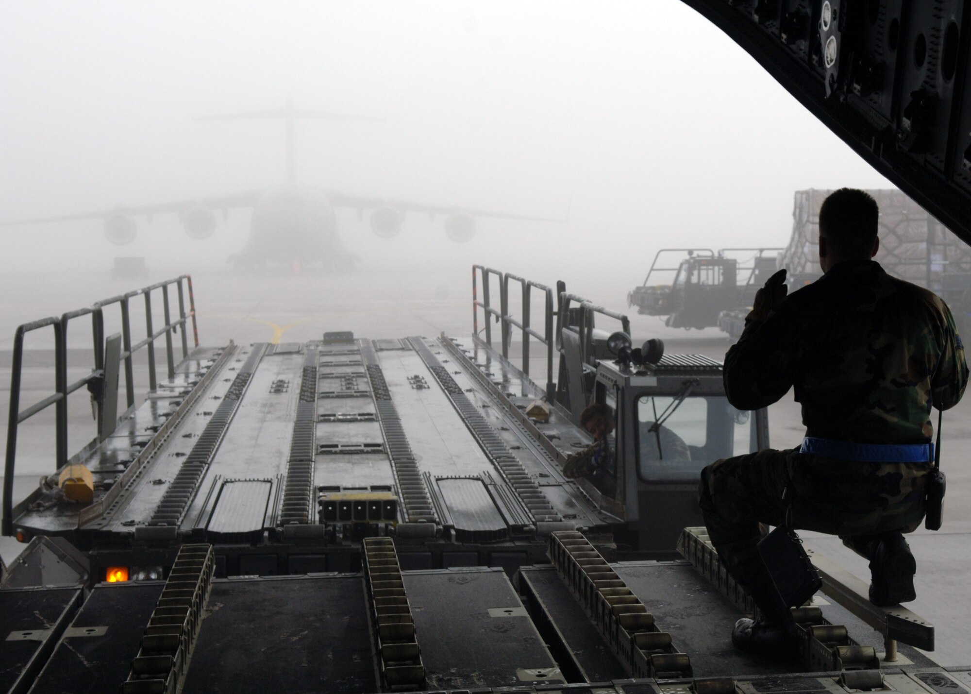 Staff Sgt. Kris Neal, 723rd Air Mobility Squadron aerial port expeditor team chief, marshals a 60K loader while offloading cargo at Ramstein Feb. 7. The cargo movement is in support of Joint Task Force-Nomad Fire in Africa. Photo by Airman 1st Class Kelly LeGuillon