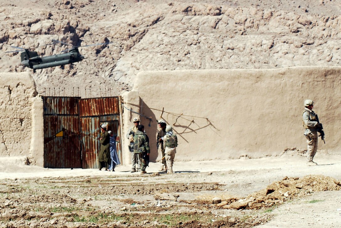 Marines with a Marine Special Operations Company secure an area of a Helmand Province village in which they were under attack by Taliban fighters, while a Chinook CH-47 pulls in to provide support for the Marines. Afghan National Army soldiers and MSOC Marines were visiting the southern Afghanistan village when they were attacked by Taliban fighters in late February. Photo by Marine Staff Sgt. Luis P. Valdespino Jr.