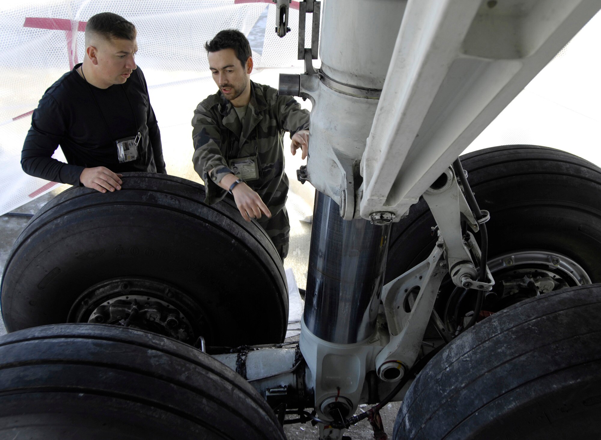 MANAS AIR BASE, Kyrgyzstan -- Tech. Sgt. Charlie Peckham, 376th Expeditionary Air Maintenance Squadron KC-135 maintainer, and Sergeant Mariau Cyril, French military unit, discuss maintenance repairs for the main landing gear on the French CF-135 at Manas Air Base in Kyrgyzstan on Feb. 23. Sergeant Peckham is originally from Vacaville, Calif., and deployed from the 92nd Maintenance Squadron at Fairchild. (U.S. Air Force/Senior Airman Tabitha Kuykendall)