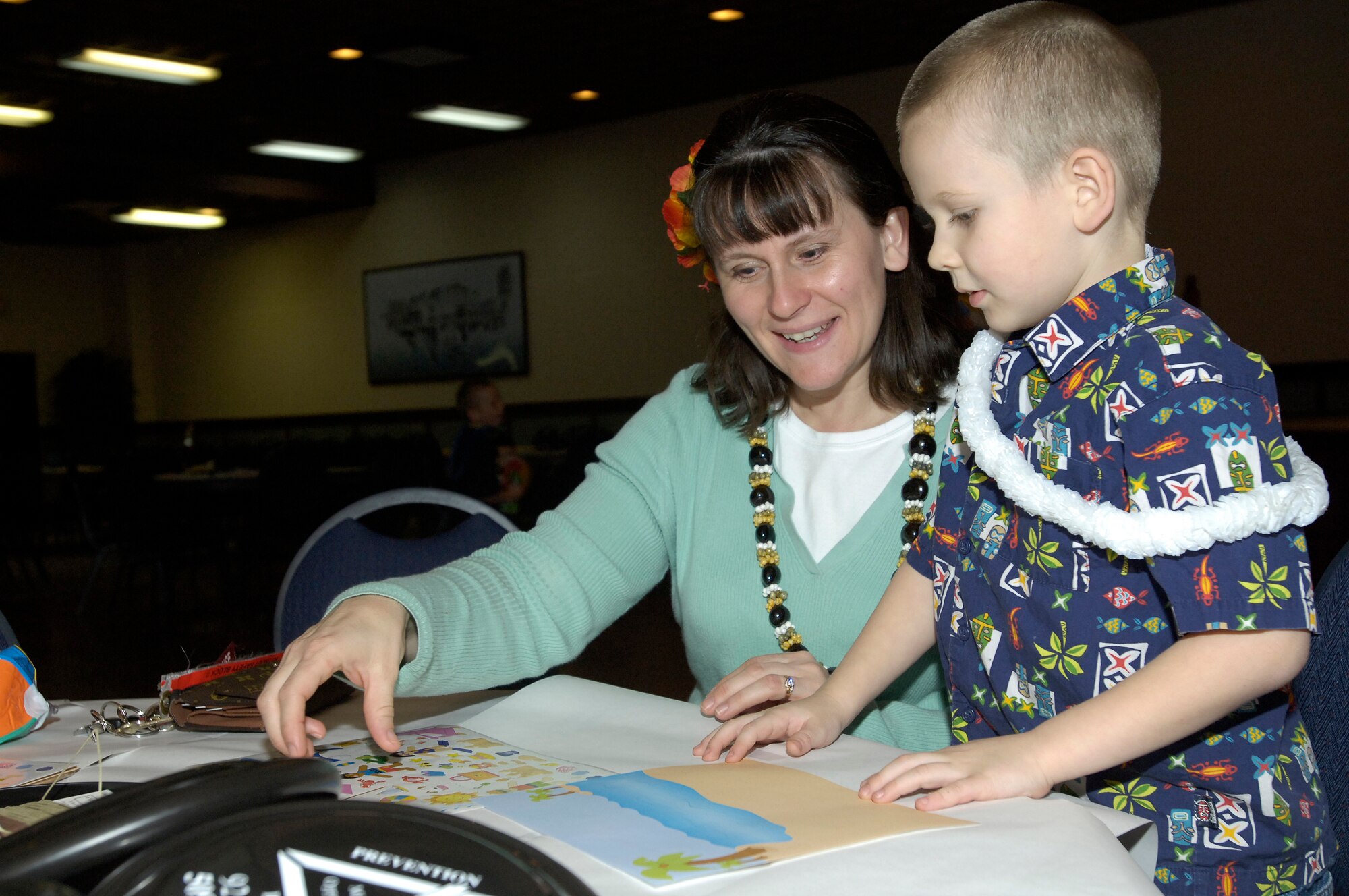 FAIRCHILD AIR FORCE BASE, Wash. – Michelle Edwards helps her son, Noah, with a collage during the 92nd Operations Group Sponsor Night at Club Fairchild Feb. 22. The Hawaiian-themed sponsor night was one of many events sponsored by various units on base for members of Team Fairchild and their families. (U.S. Air Force photo/Senior Airman Eunique Stevens)