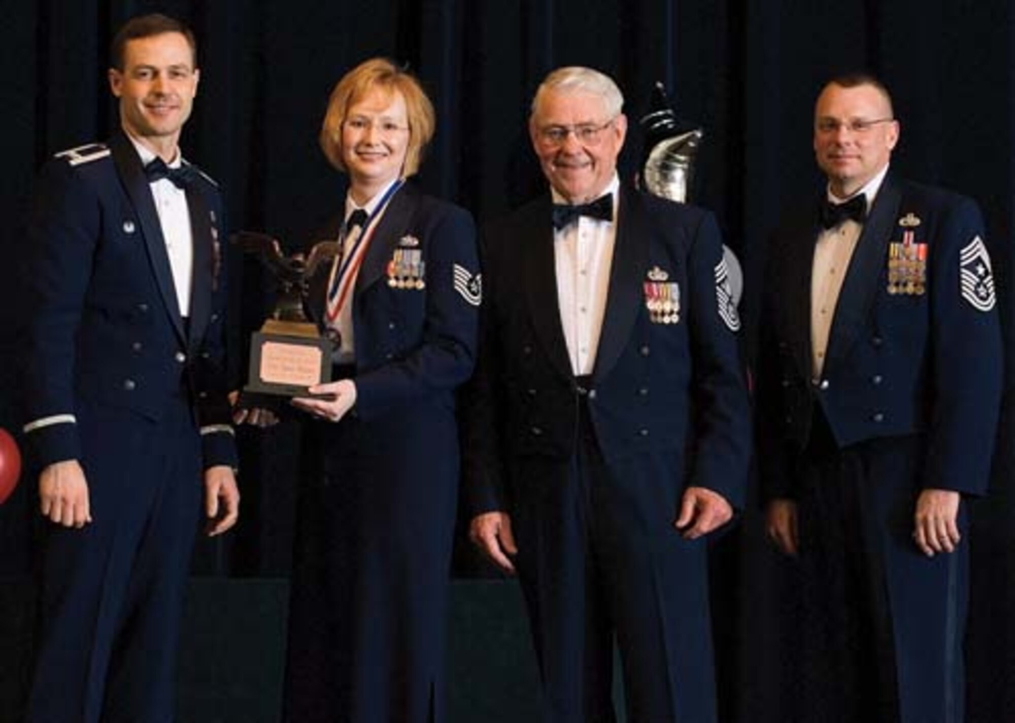 Col. Steven Harrison, 436th Airlift Wing commander, Tech. Sgt. Donna Dickson, 436th Maintenance Squadron, retired Chief Master Sgt. Robert Gaylor, the fifth Chief Master Sgt. of the Air Force, and Chief Master Sgt. John Wood, 436th AW command chief, assemble on stage at the 436th Airlift Wing’s 2007 Annual Awards Banquet as Sergeant Dickson is presented her trophy. Sergeant Dickson was named the NCO of the Year, 2007. (U.S. Air Force photo/Roland Balik)