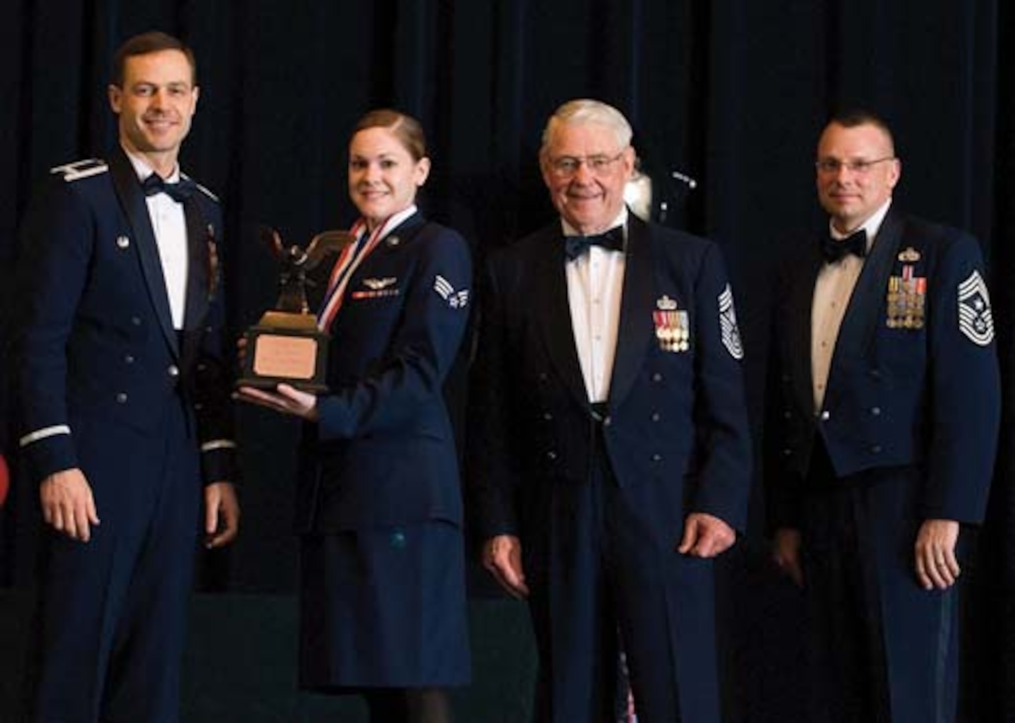 Col. Steven Harrison, 436th Airlift Wing commander, Senior Airman Tara Minguez, 9th Airlift Squadron, retired Chief Master Sgt. Robert Gaylor, the fifth Chief Master Sgt. of the Air Force, and Chief Master Sgt. John Wood, 436th AW command chief, assemble on stage at the 436th Airlift Wing’s 2007 Annual Awards Banquet as Airman Minguez is presented her trophy. Airman Minguez was named the Airman of the Year, 2007. (U.S. Air Force photo/Roland Balik)
