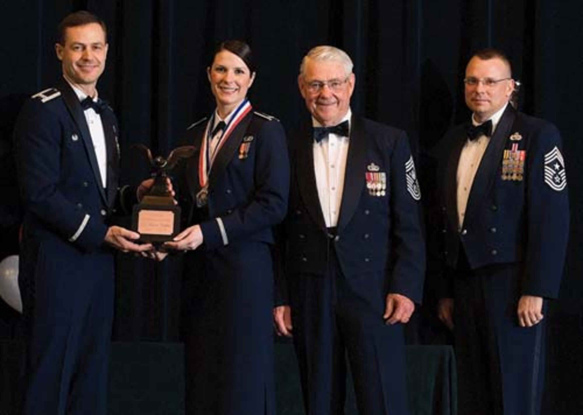 Col. Steven Harrison, 436th Airlift Wing commander, 1st Lt. Megan Schmid, 436th AW, retired Chief Master Sgt. Robert Gaylor, the fifth Chief Master Sgt. of the Air Force, and Chief Master Sgt. John Wood, 436th AW command chief, assemble on stage at the 436th Airlift Wing’s 2007 Annual Awards Banquet as Lieutenant Schmid is presented her trophy. Lieutenant Schmid was named the Junior Company Grade Officer of the Year, 2007. (U.S. Air Force photo/Roland Balik)