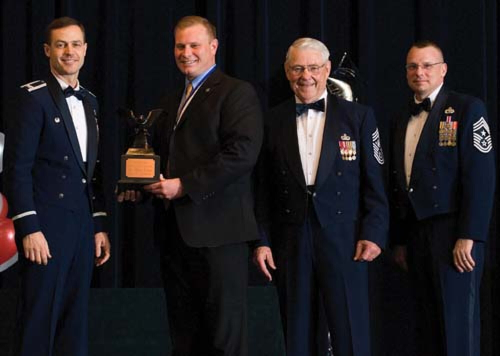 Col. Steven Harrison, 436th Airlift Wing commander, Brian Roush, 436th Services Squadron, retired Chief Master Sgt. Robert Gaylor, the fifth Chief Master Sgt. of the Air Force, and Chief Master Sgt. John Wood, 436th AW command chief, assemble on stage at the 436th Airlift Wing’s 2007 Annual Awards Banquet as Mr. Roush is presented his trophy. Mr. Roush was named the Civilian of the Year, Category III, 2007. (U.S. Air Force photo/Roland Balik)