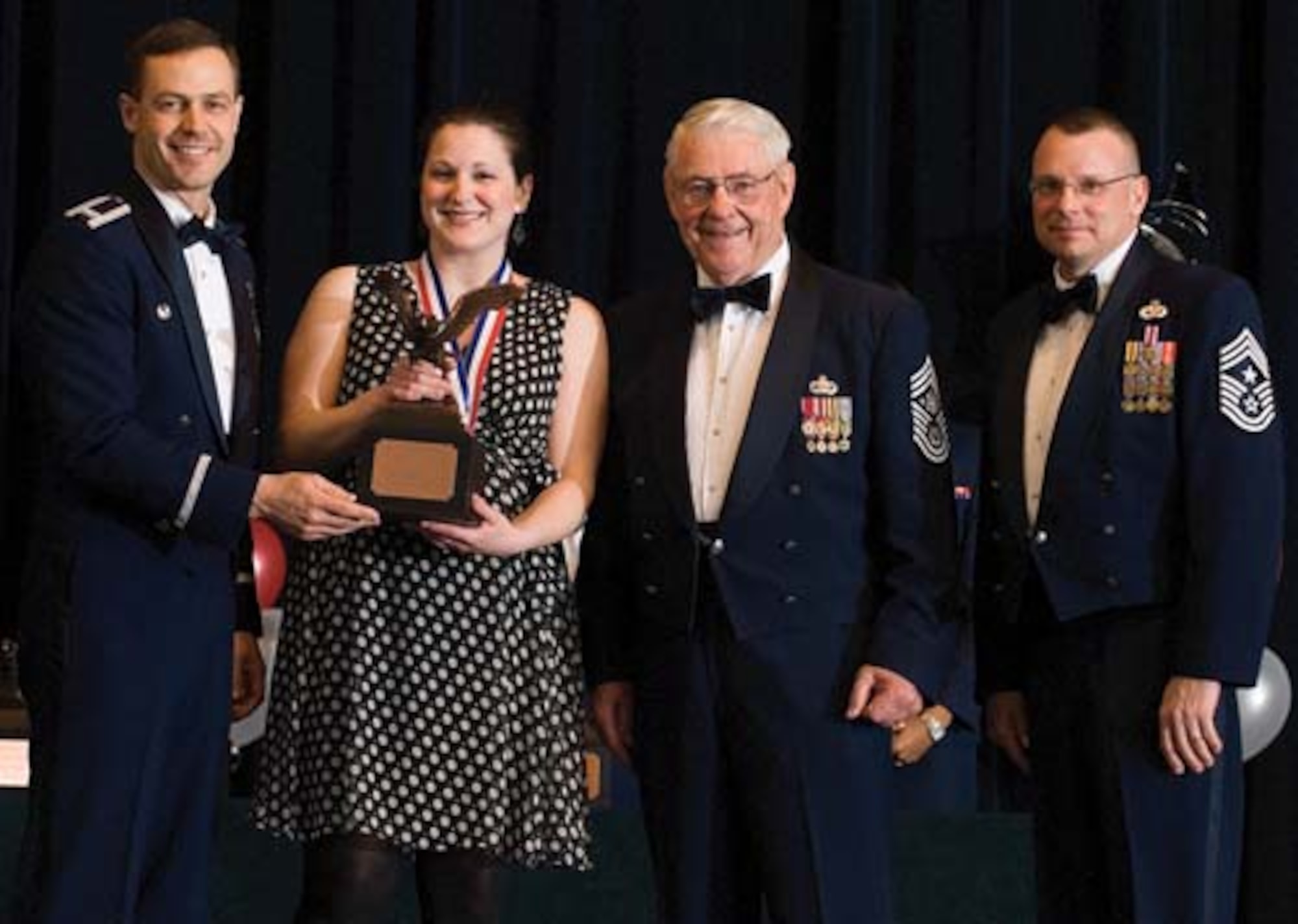 Col. Steven Harrison, 436th Airlift Wing commander, Kristina Eash, 436th Operations Group, retired Chief Master Sgt. Robert Gaylor, the fifth Chief Master Sgt. of the Air Force, and Chief Master Sgt. John Wood, 436th AW command chief, assemble on stage at the 436th Airlift Wing’s 2007 Annual Awards Banquet as Ms. Eash is presented her trophy. Ms. Eash was named the Civilian of the Year, Category I, 2007. (U.S. Air Force photo/Roland Balik)