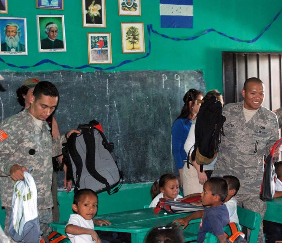 Army Sgt. 1st Class Julio Reyes and Staff Sgt. Matthew Delgado give backpacks packed with school supplies to children at a school Feb. 21 in Humuya, Honduras. Five representatives from the Give a Kid a Backpack Organization in Florida and 15 volunteers from Joint Task Force-Bravo from Soto Cano Air Base, Honduras, distributed more than 700 backpacks packed with school supplies to children at five schools and two orphanages in the Comayagua and La Paz districts. Sergeant Delgado is a JTF-Bravo Joint Operations Center controller. (U.S. Air Force photo/Tech. Sgt John Asselin) 