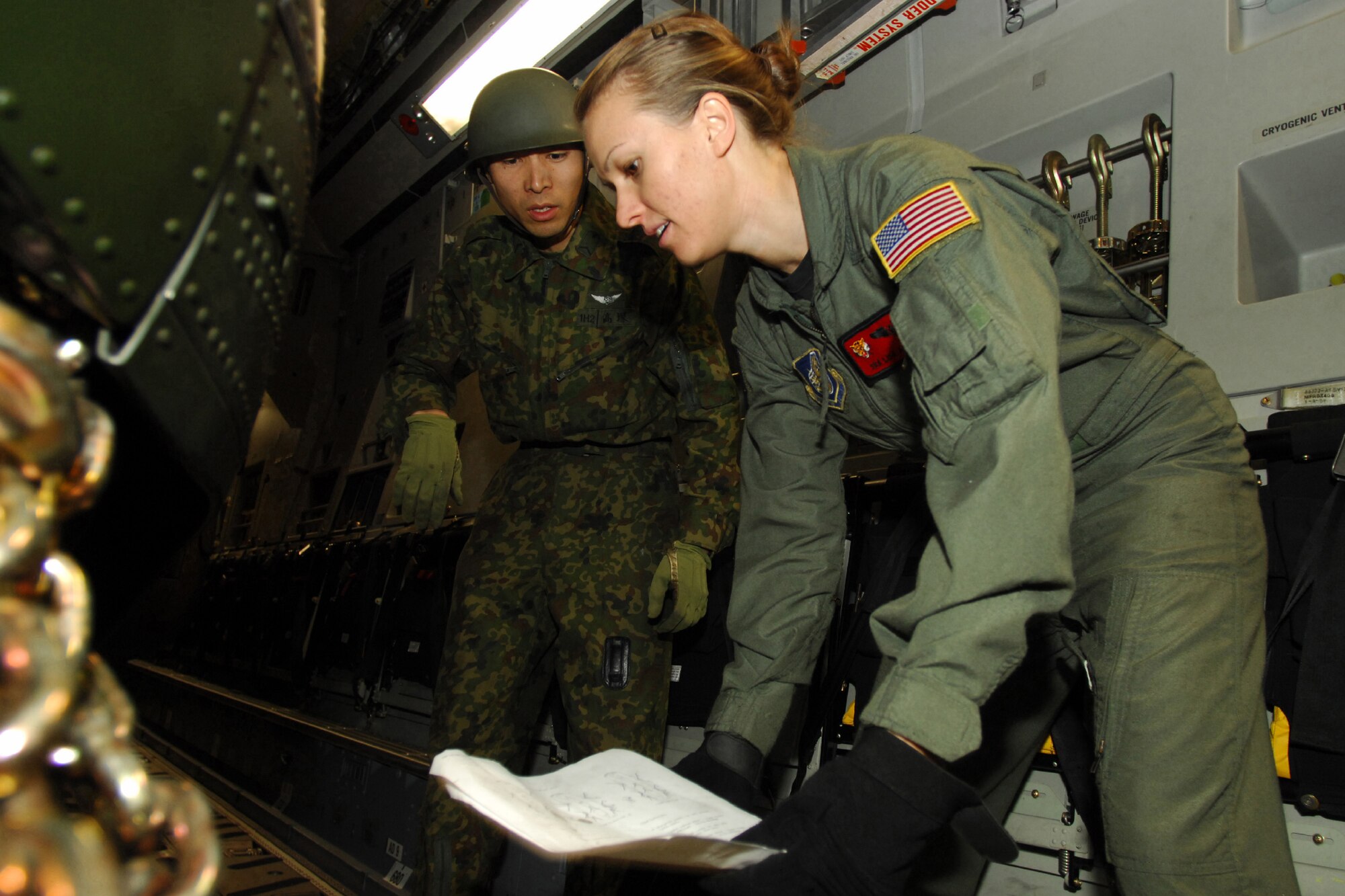 YOKOTA AIR BASE, Japan -- U.S. Air Force Senior Airman Lisa Long, right, and a Japan Ground Self Defense Force member, load a JGSDF CH-47J Chinook helicopter into a U.S. Air Force C-17 Globemaster III cargo plane Feb. 23. It was the first time a Japanese helicopter was loaded into another nation's aircraft. The demonstration was conducted the last morning of the Pacific Global Air Mobility Seminar held Feb. 22 and 23. Sergeant Boehm is a loadmaster assigned to the 535th Airlift Squadron, Hickam Air Force Base, Hawaii. The C-17 is also assigned to the 535th Airlift Squadron. The CH-47J is assigned to the 1st Helicopter Brigade at JGSDF Camp Kisarazu in Kisarazu City, Chiba Prefecture. (U.S. Air Force photo by Osakabe Yasuo)